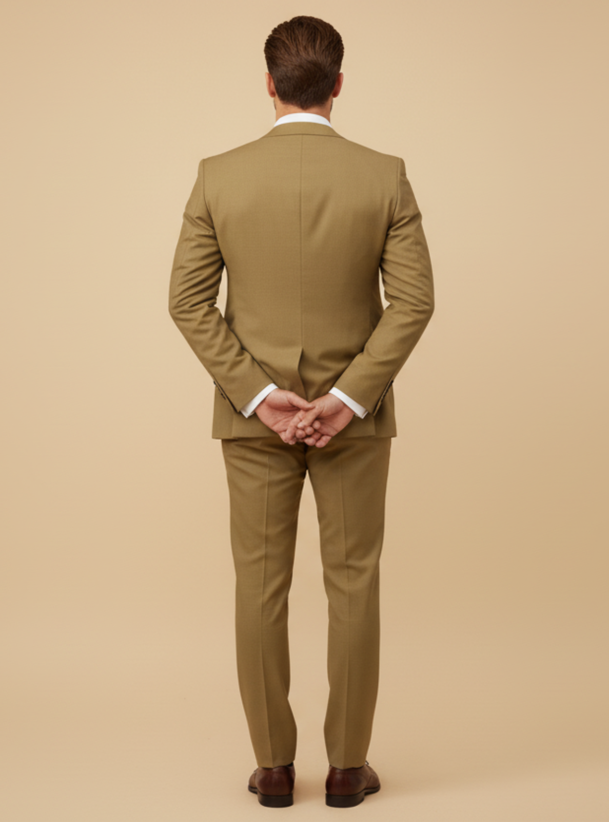 Man wearing a beige suit standing against a beige background
