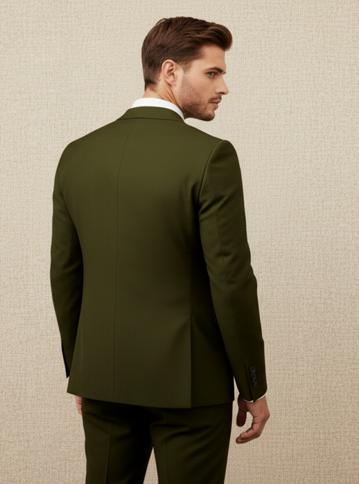 Man wearing a green suit standing against a beige wall
