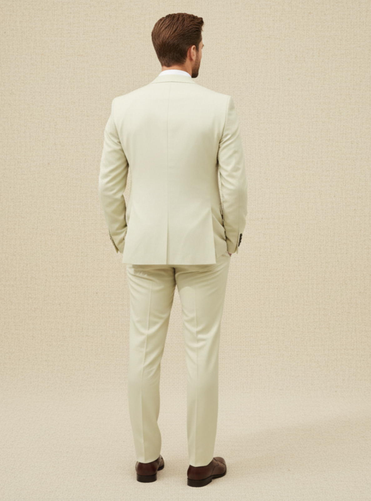 Man wearing a light green suit standing against a beige background