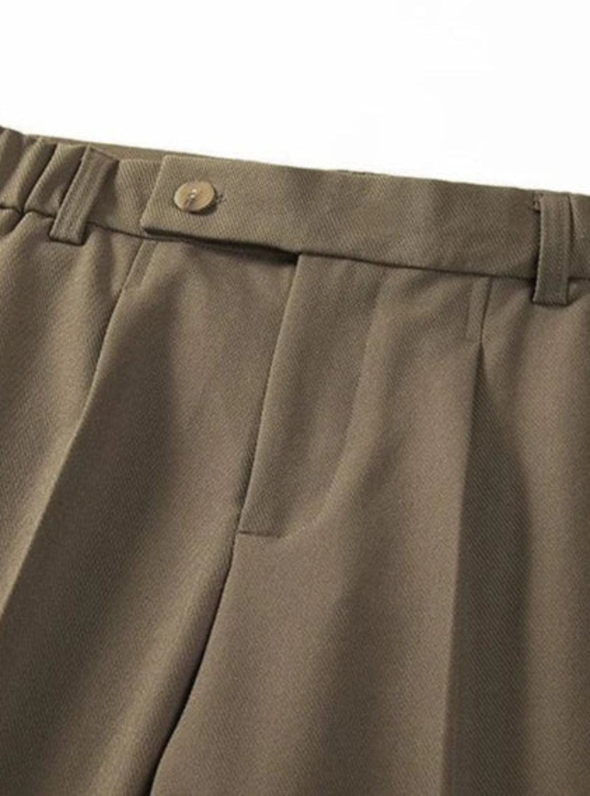 Close-up of brown pleated pants with a button on a white background