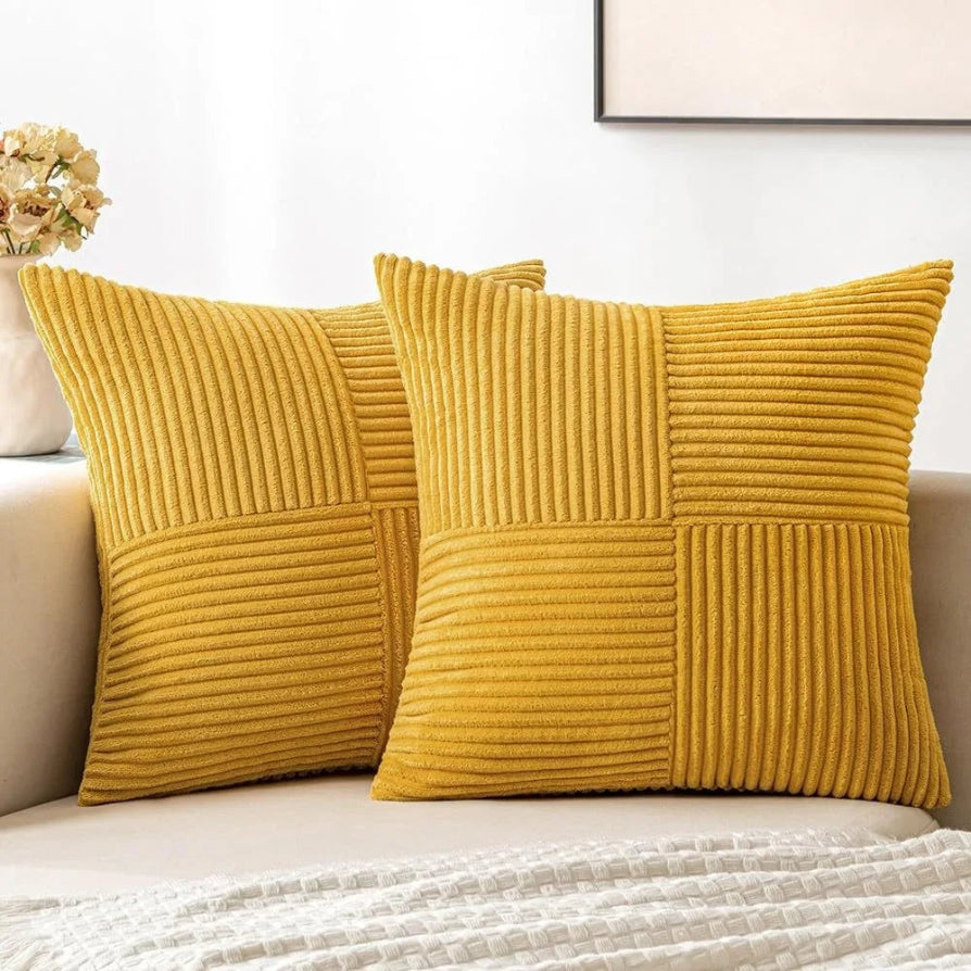 Two mustard yellow textured pillows on a beige sofa with a neutral background.