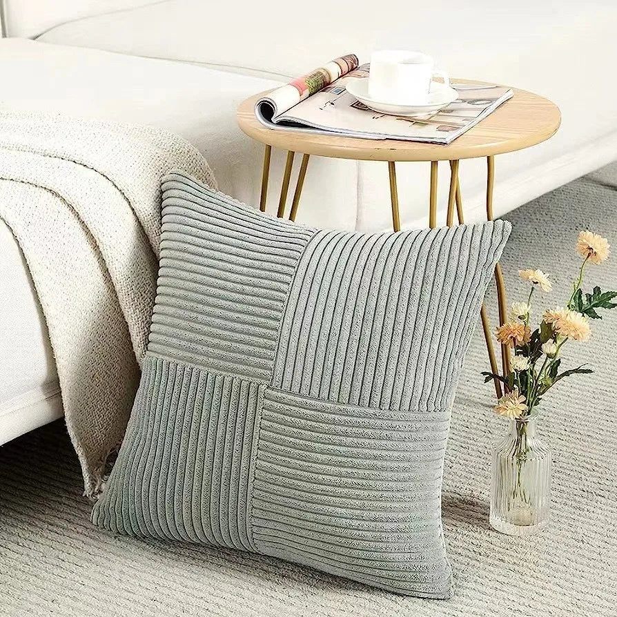 Gray textured pillow on a couch with a small table and flowers in the background