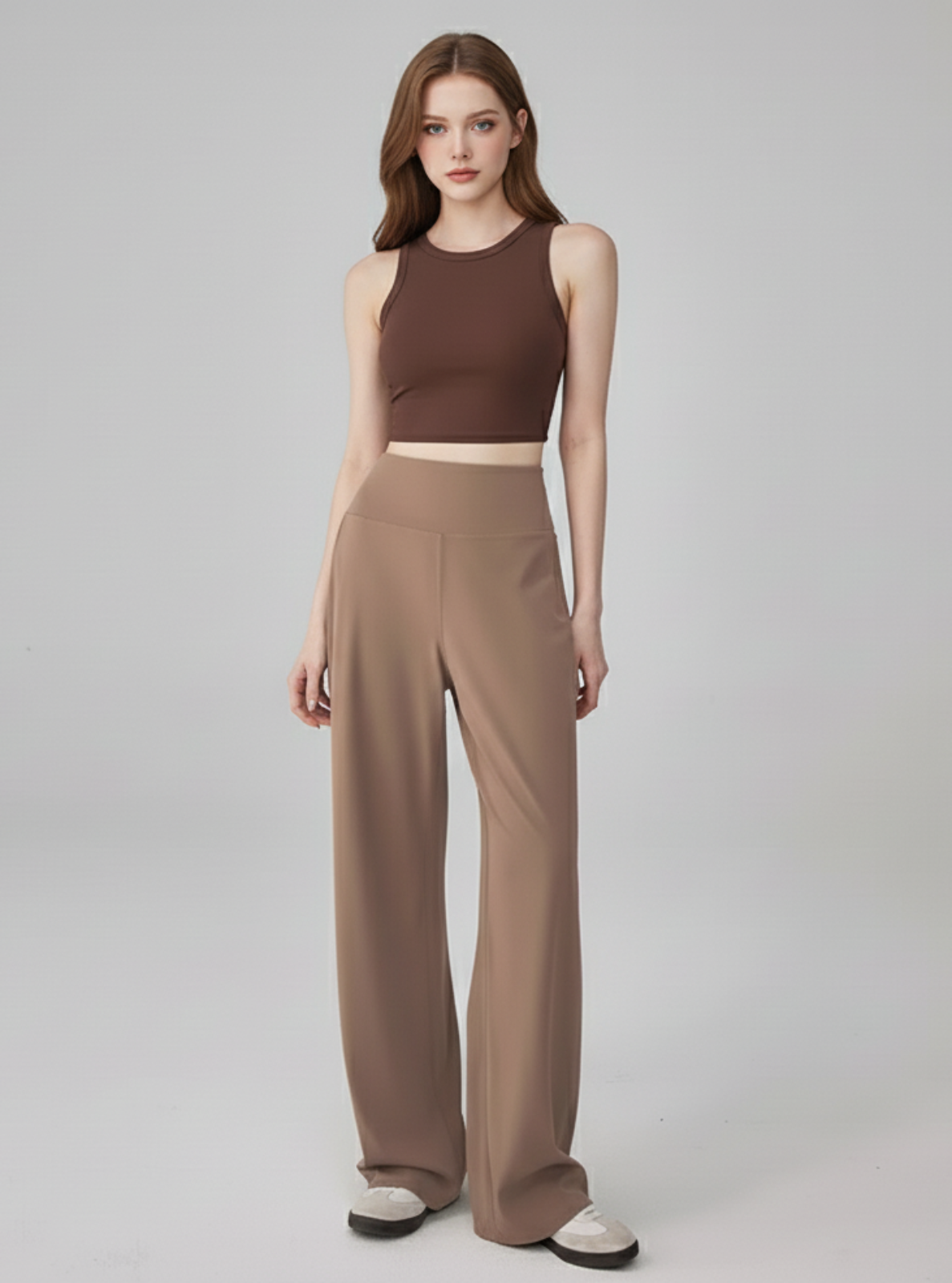 Woman wearing a brown sleeveless top and wide-leg pants on a gray background
