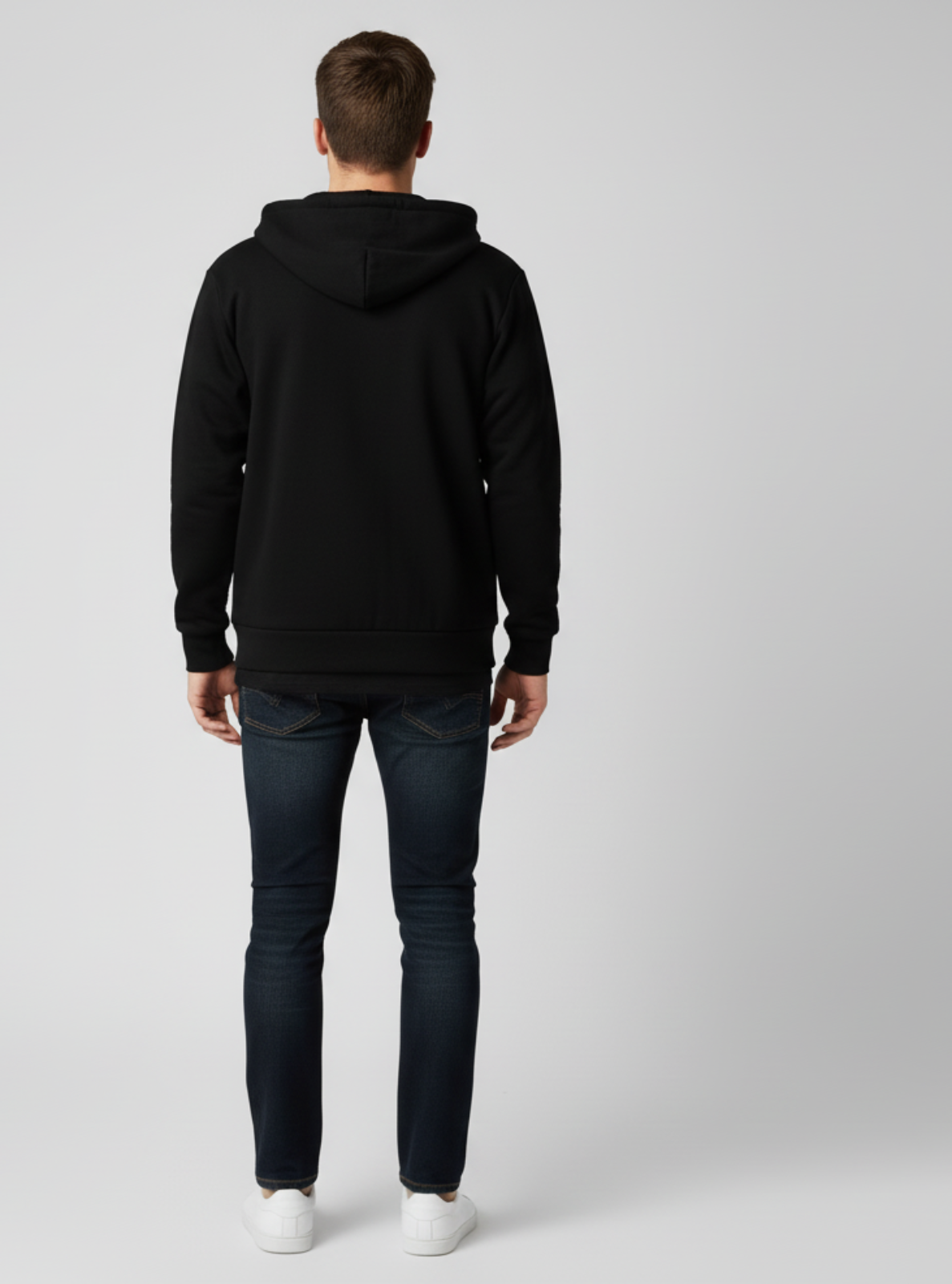 Man wearing a black hoodie and dark jeans on a white background