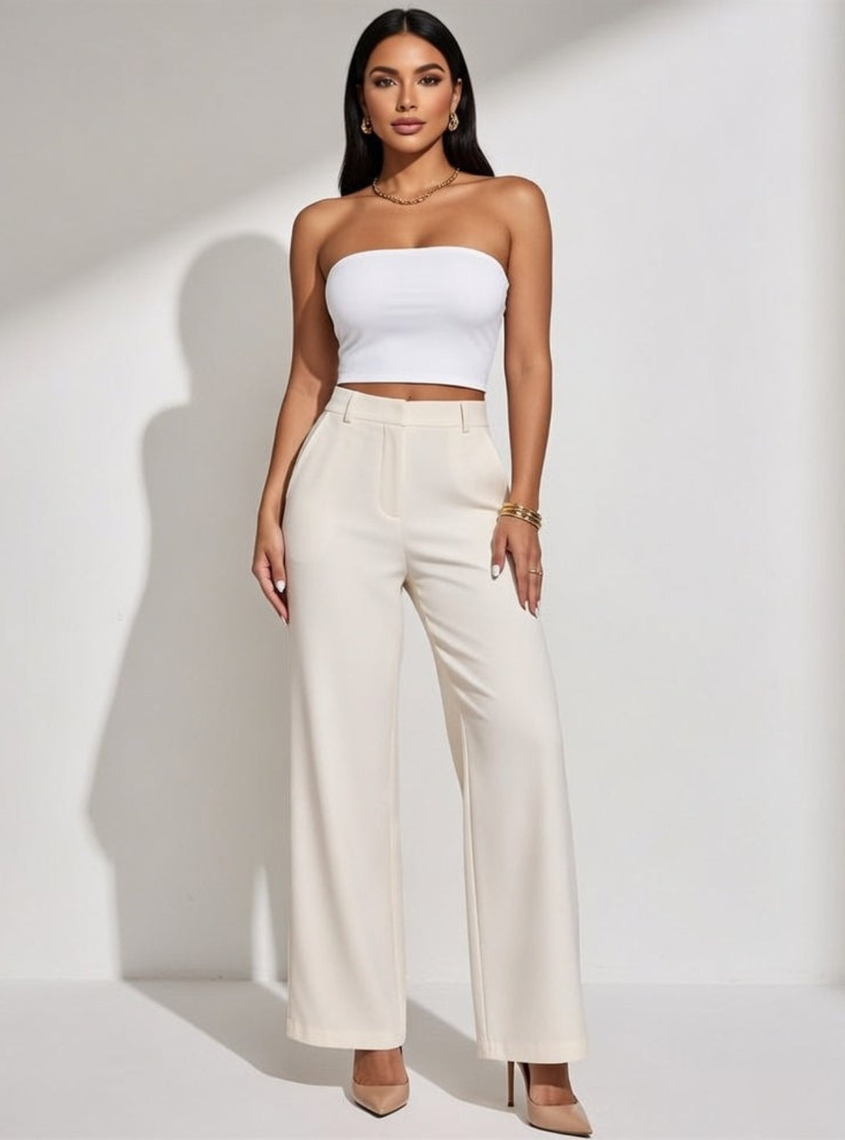 Woman wearing a white strapless top and beige wide-leg pants on a white background