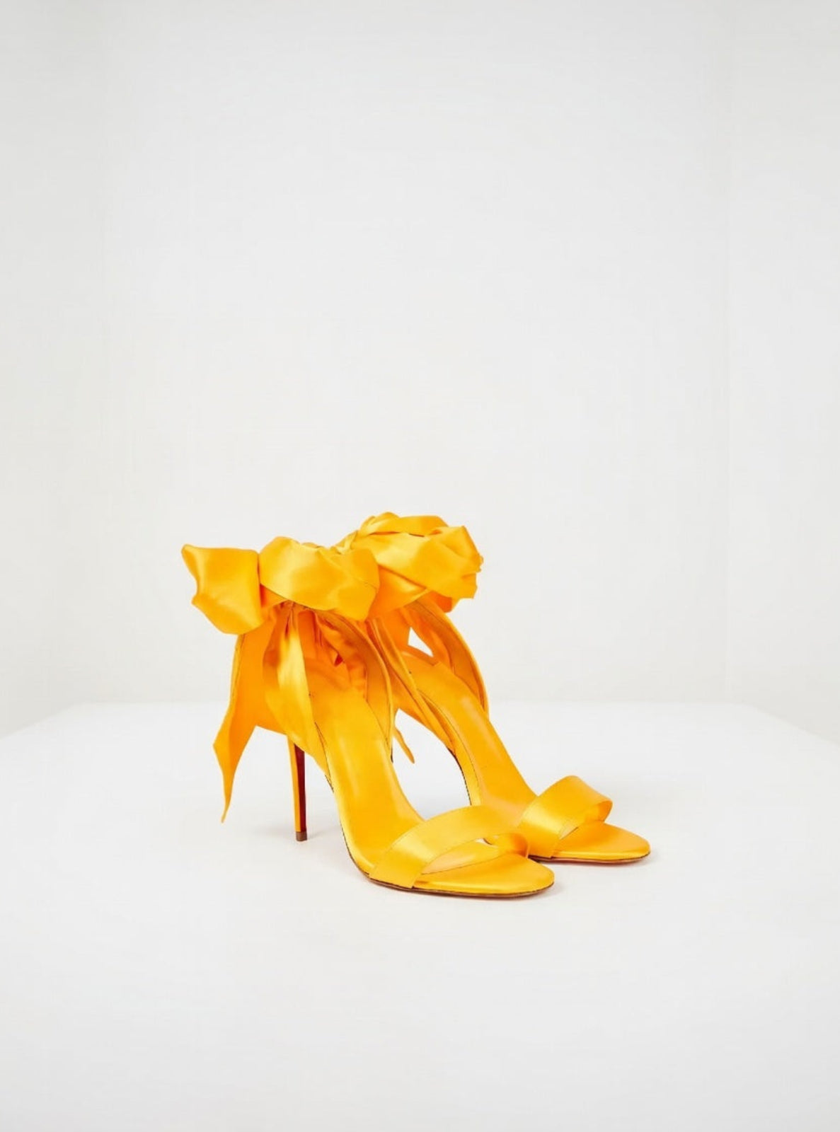 Yellow high-heeled shoes with large bows on a white background