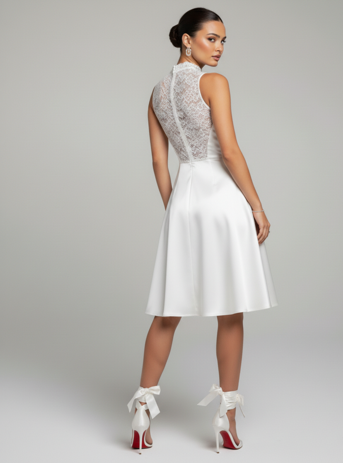 Woman wearing a white dress with lace detailing on a gray background