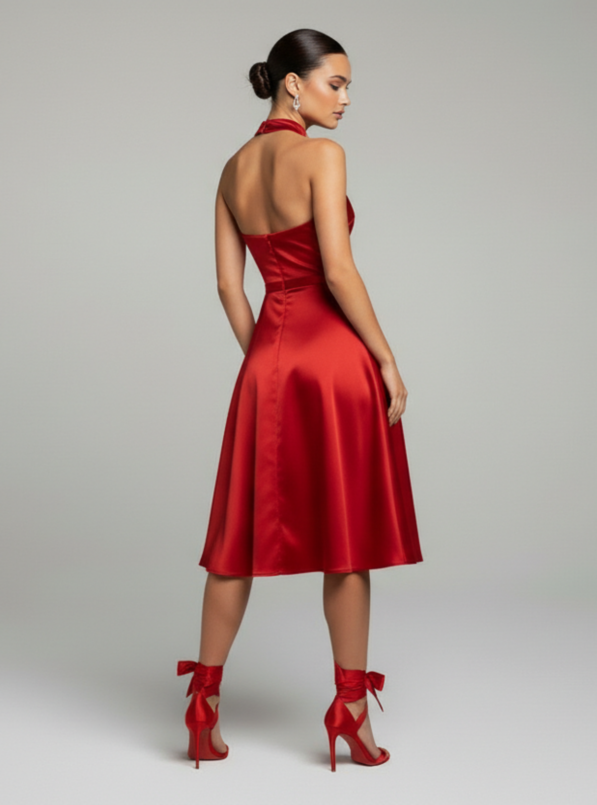Woman wearing a red dress and high heels on a gray background