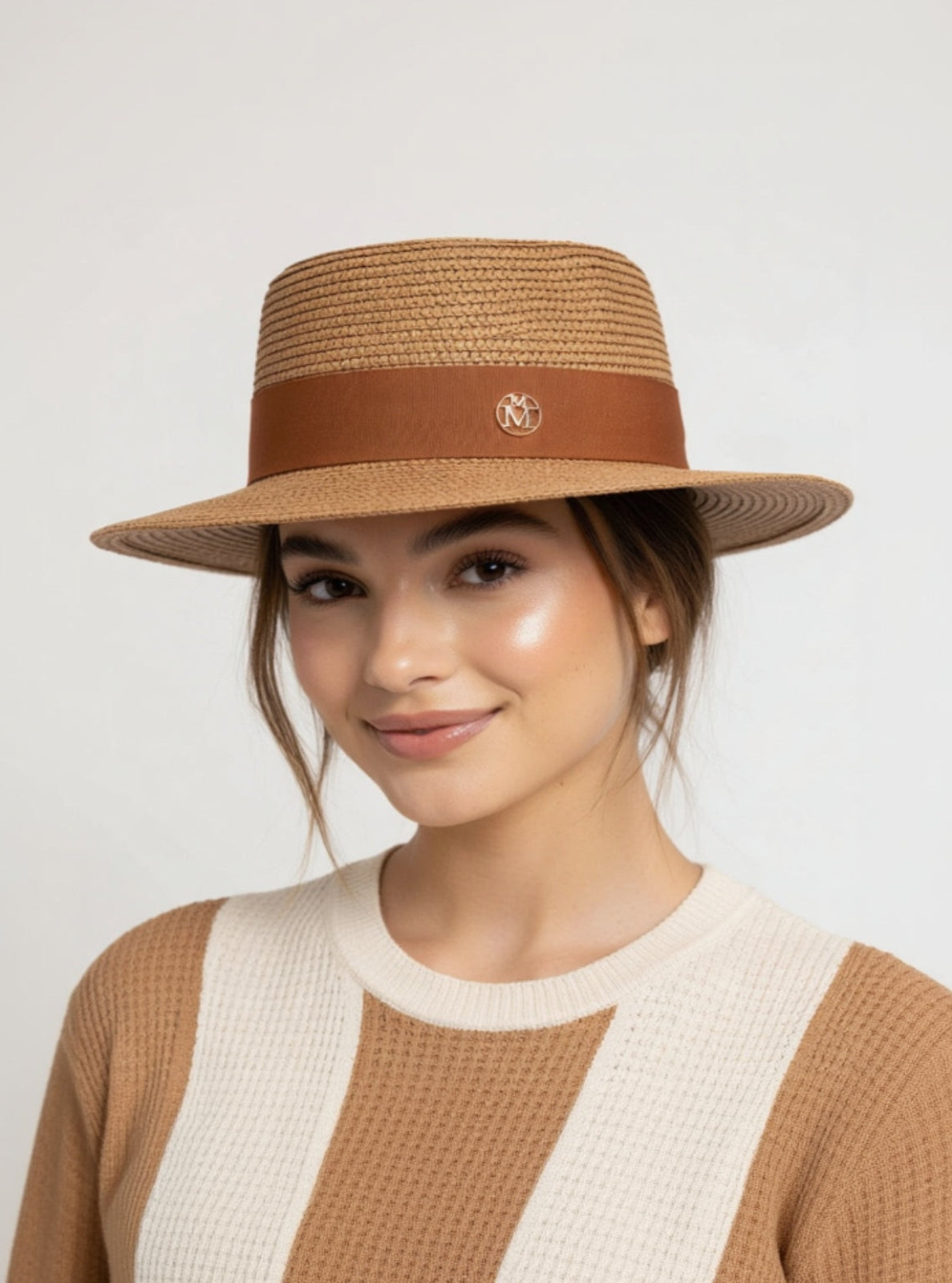 Woman wearing a brown straw hat with a leather band on a plain background
