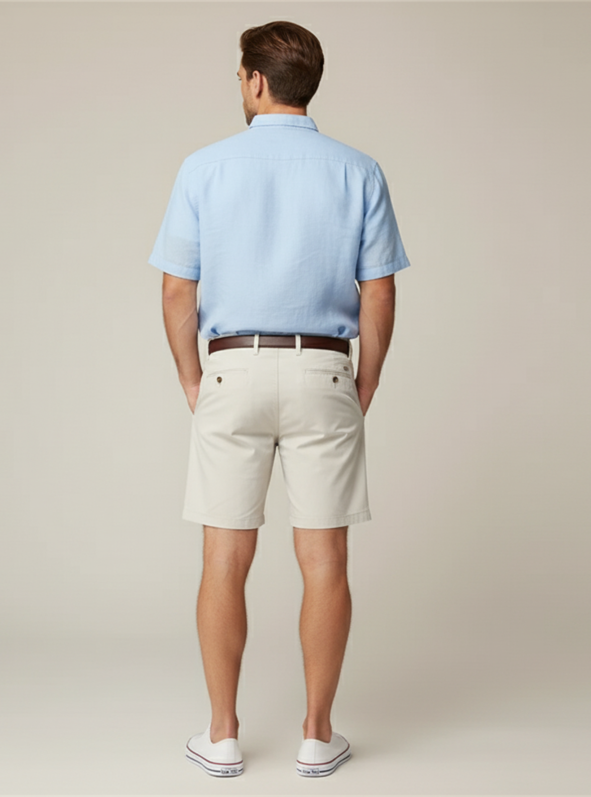 Man wearing a light blue polo shirt and beige shorts on a plain background
