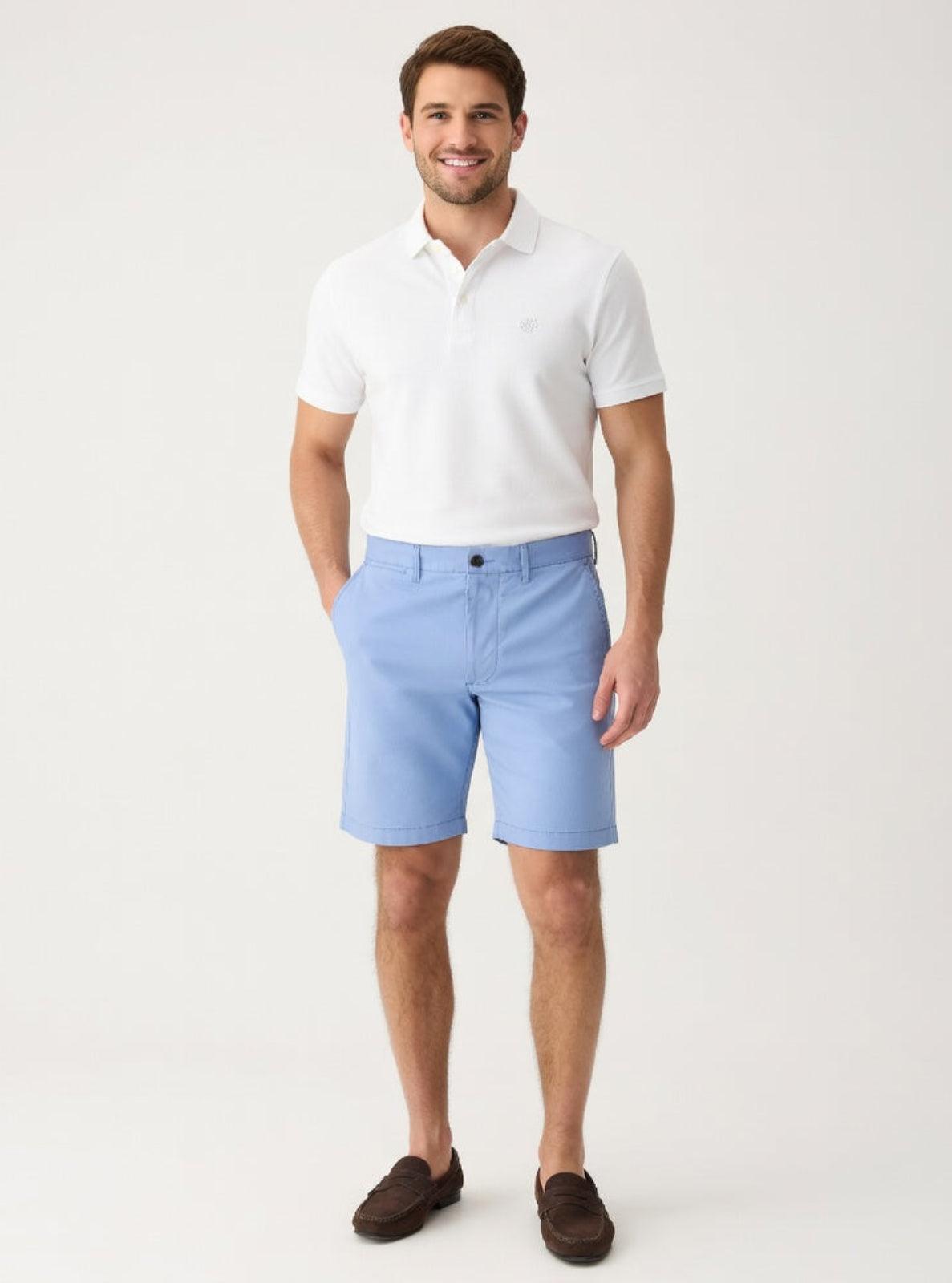 Man wearing a white polo shirt and light blue shorts on a white background