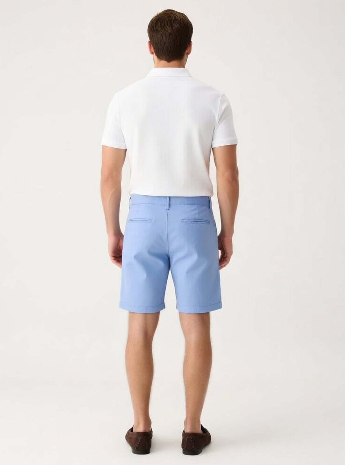Man wearing light blue shorts and a white polo shirt on a white background