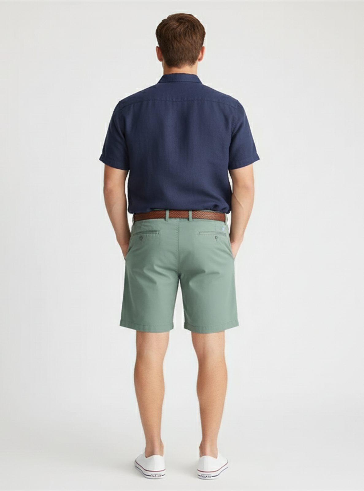 Man wearing a navy polo shirt and green shorts on a white background
