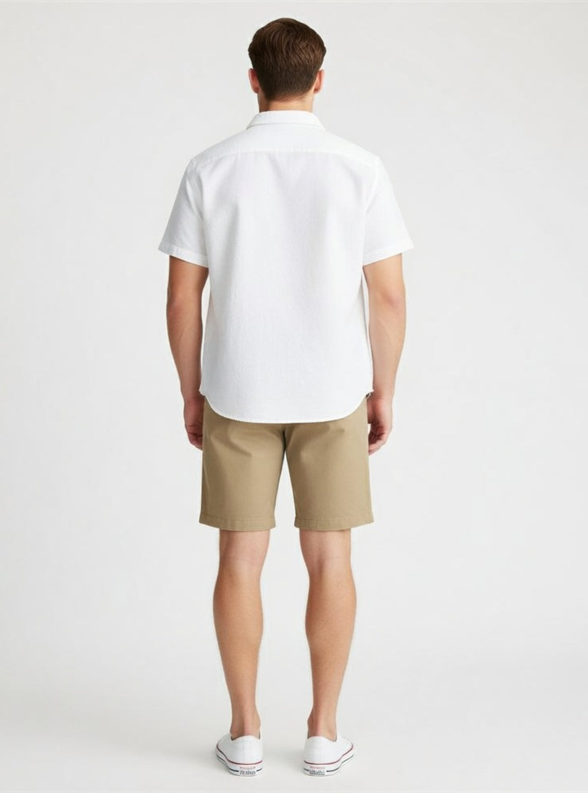 Man wearing a white shirt and beige shorts on a plain background