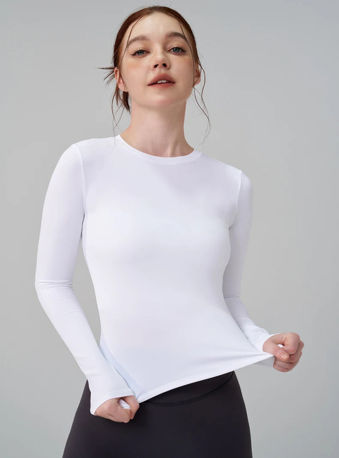 Person wearing a white long-sleeve athletic top against a gray background