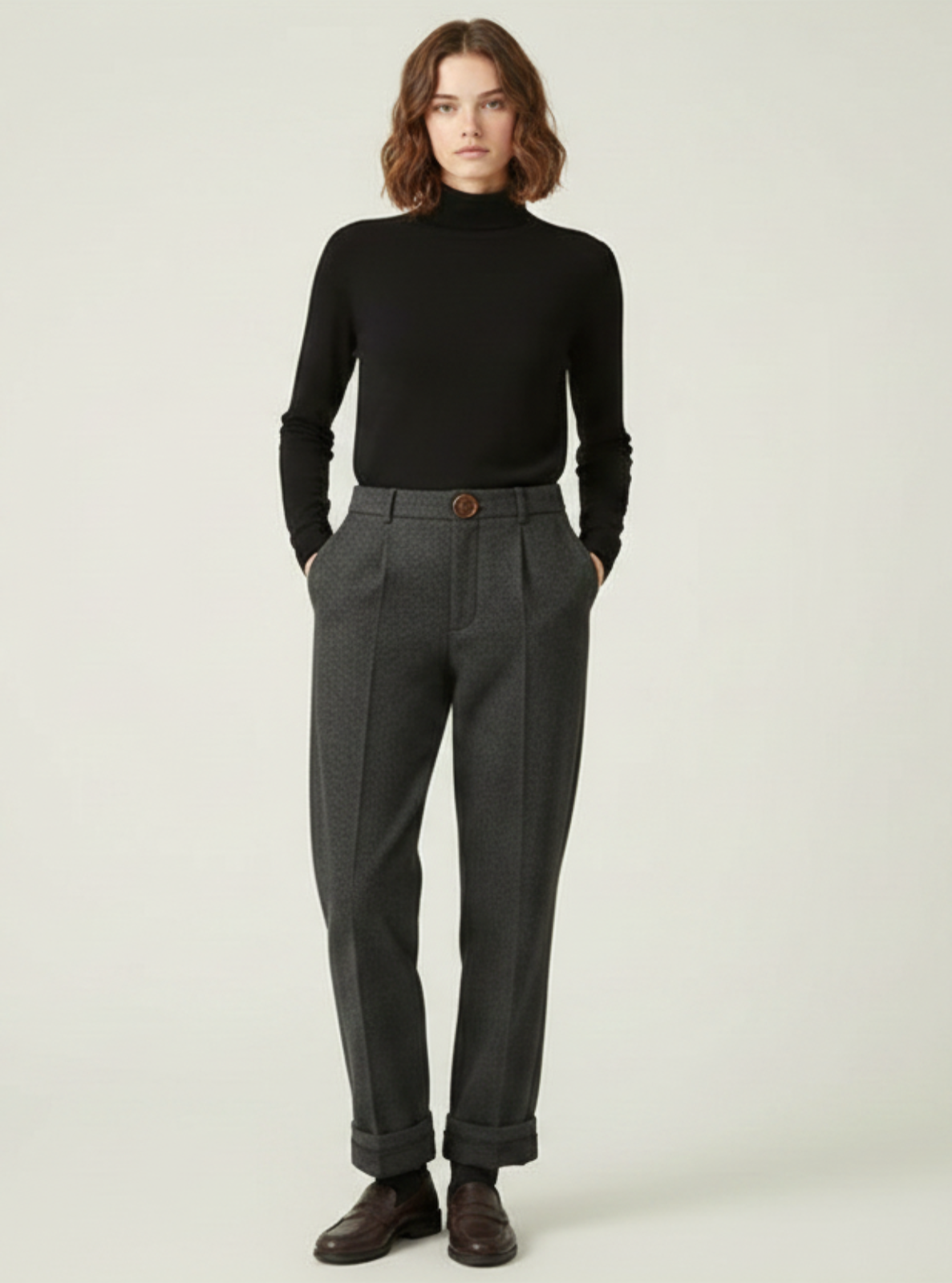 Person wearing a black turtleneck and gray pants on a white background