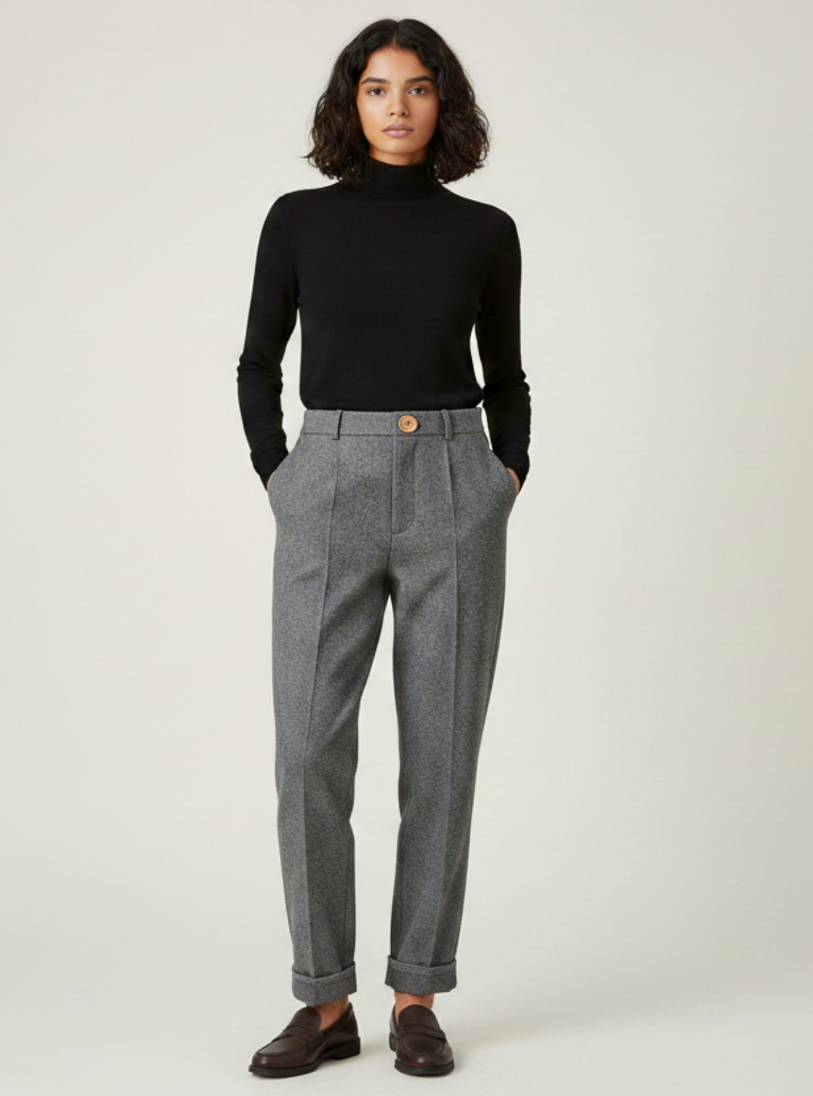 Person wearing a black turtleneck and gray checkered pants on a white background
