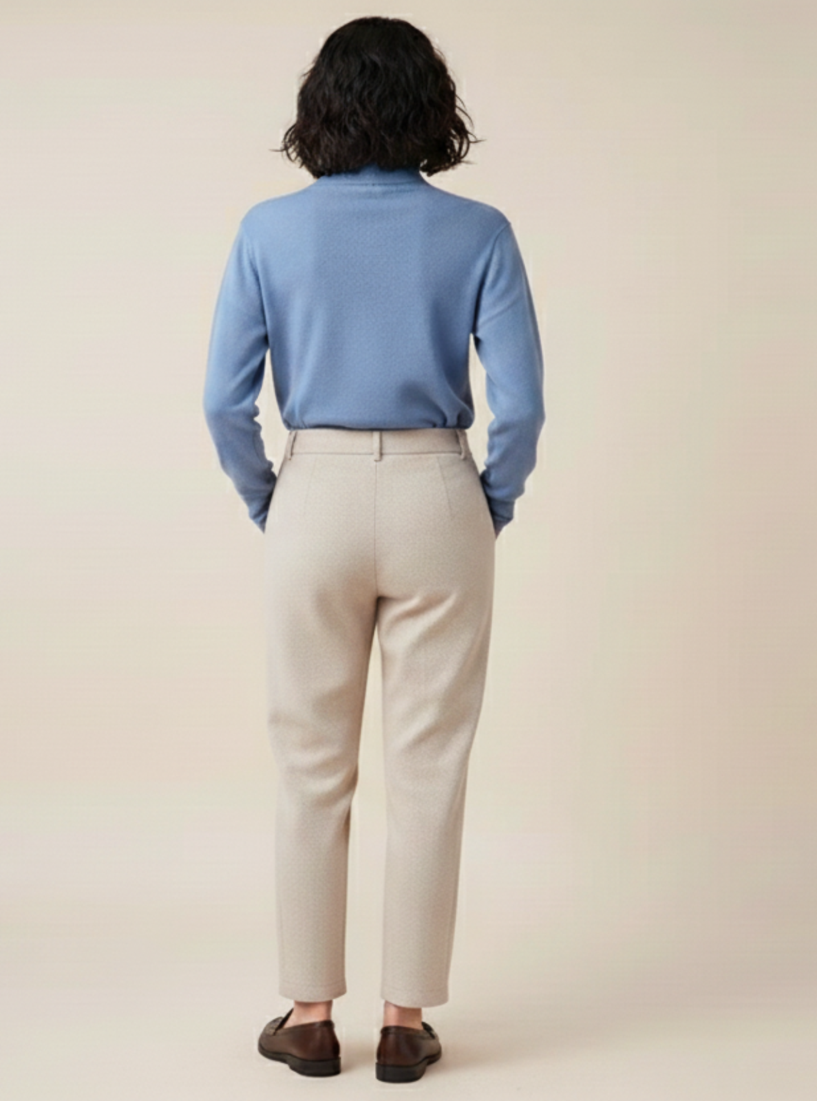 Person wearing a light blue shirt and beige pants against a plain background