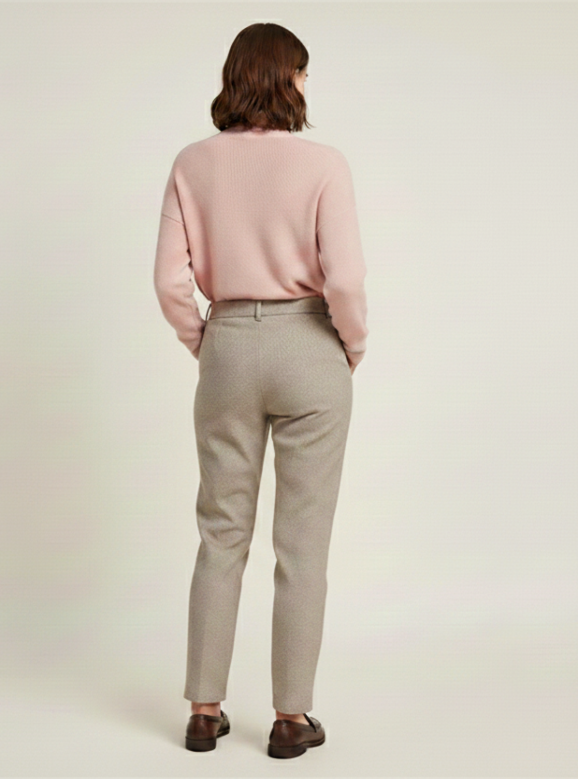 Person wearing a pink shirt and beige pants on a plain background