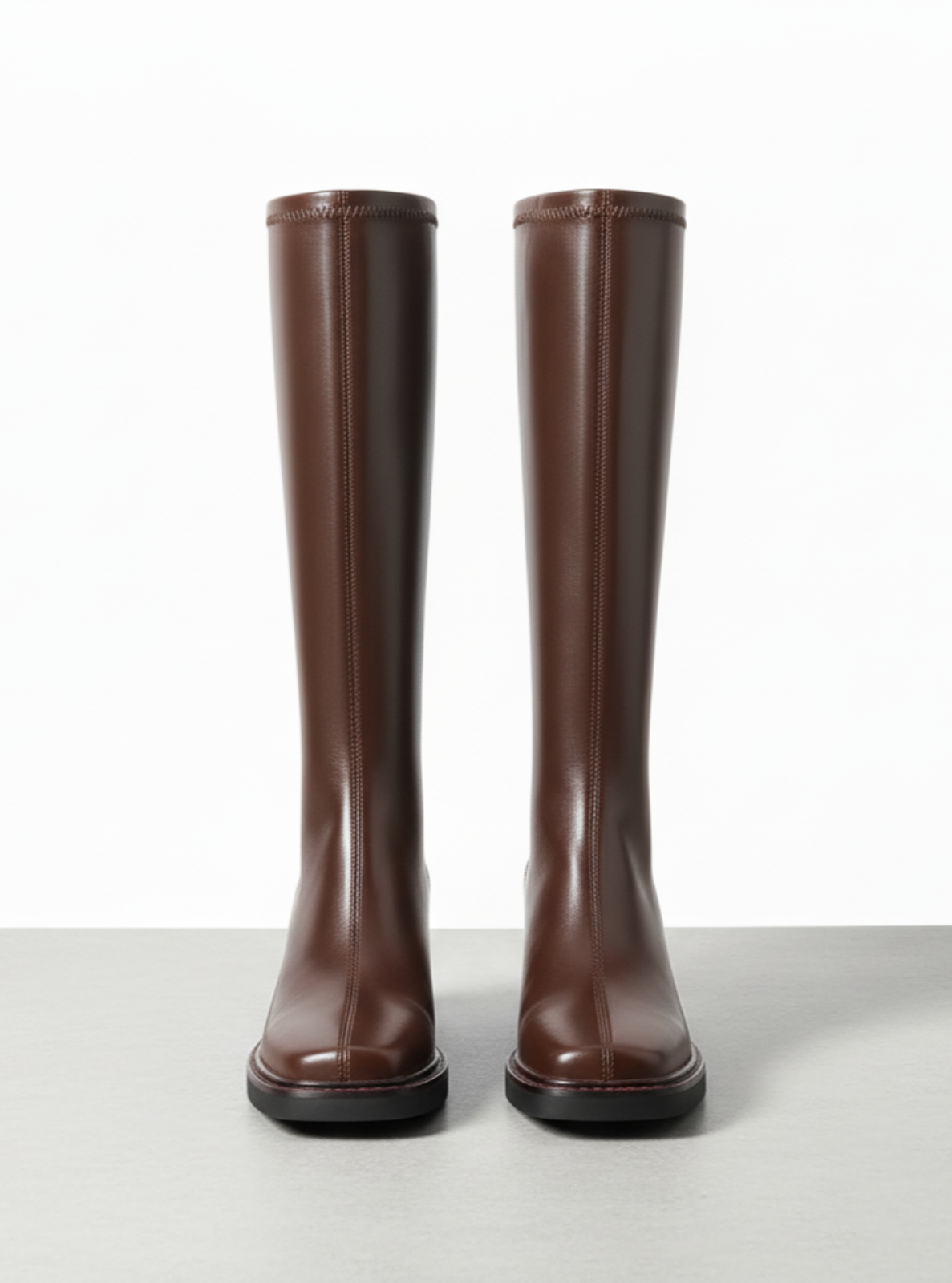 Pair of brown knee-high boots on a light gray background