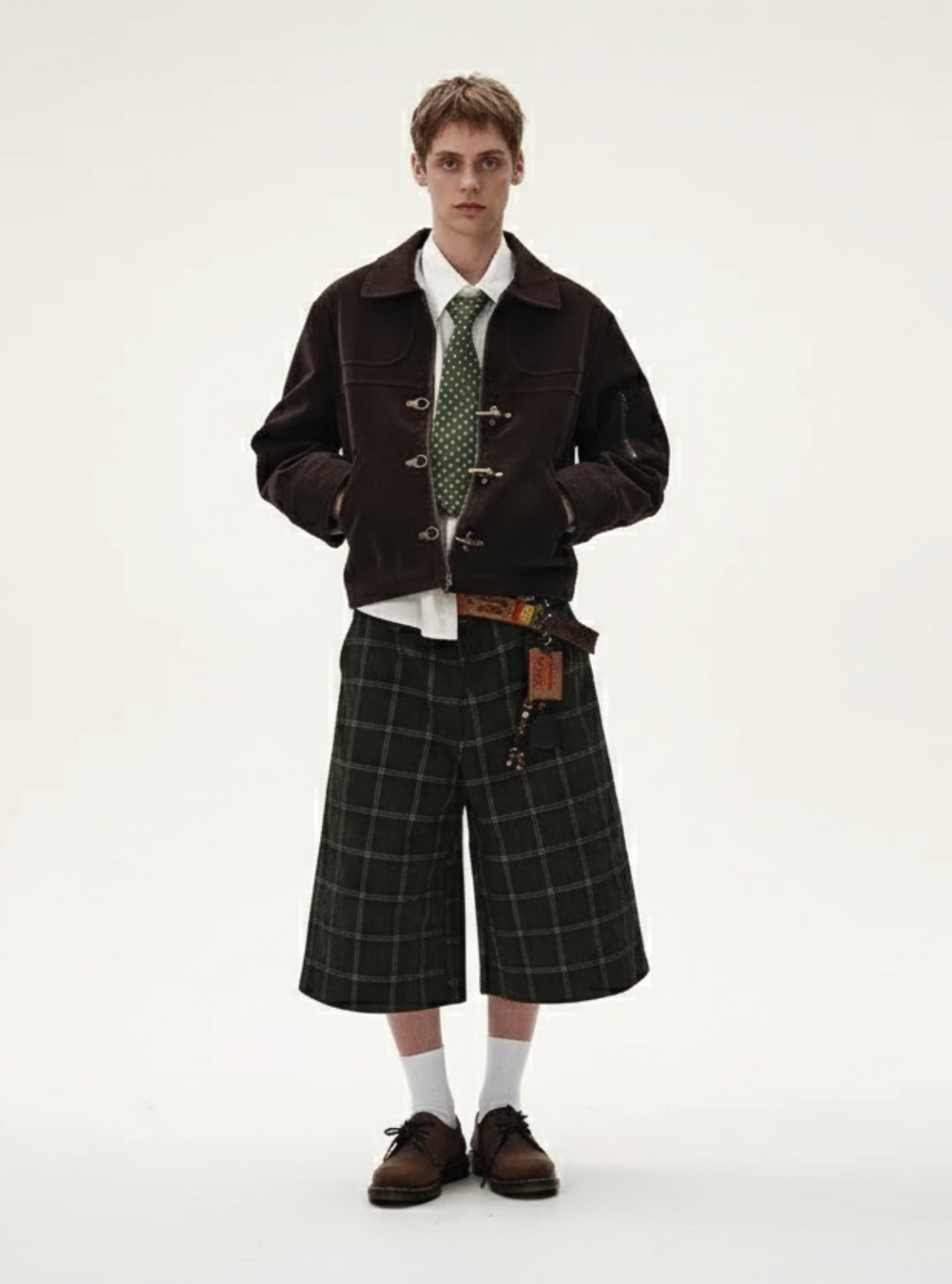 Person wearing a dark jacket, plaid skirt, and patterned tie on a white background