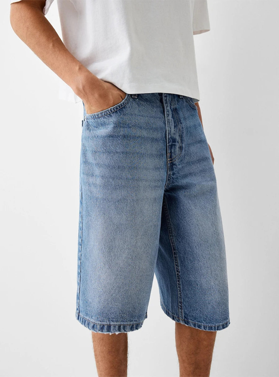 Person wearing blue denim shorts on a white background