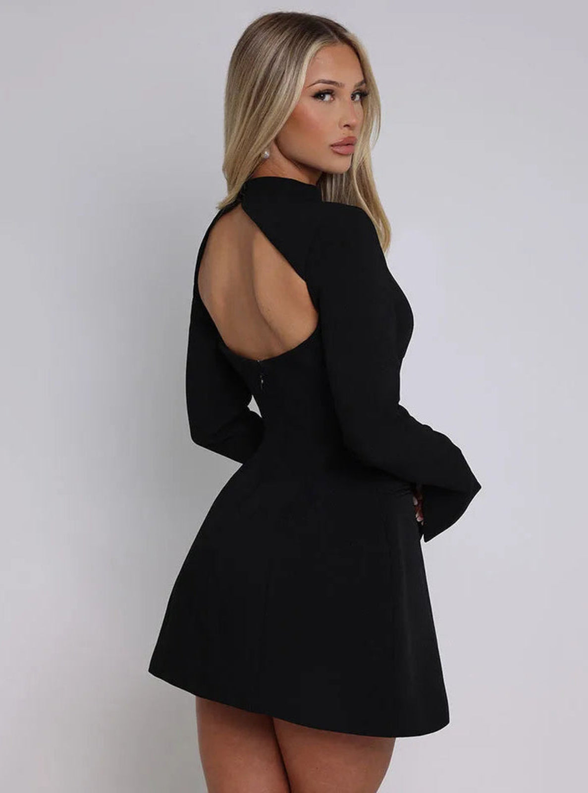 Woman wearing a black dress with cut-out back on a white background