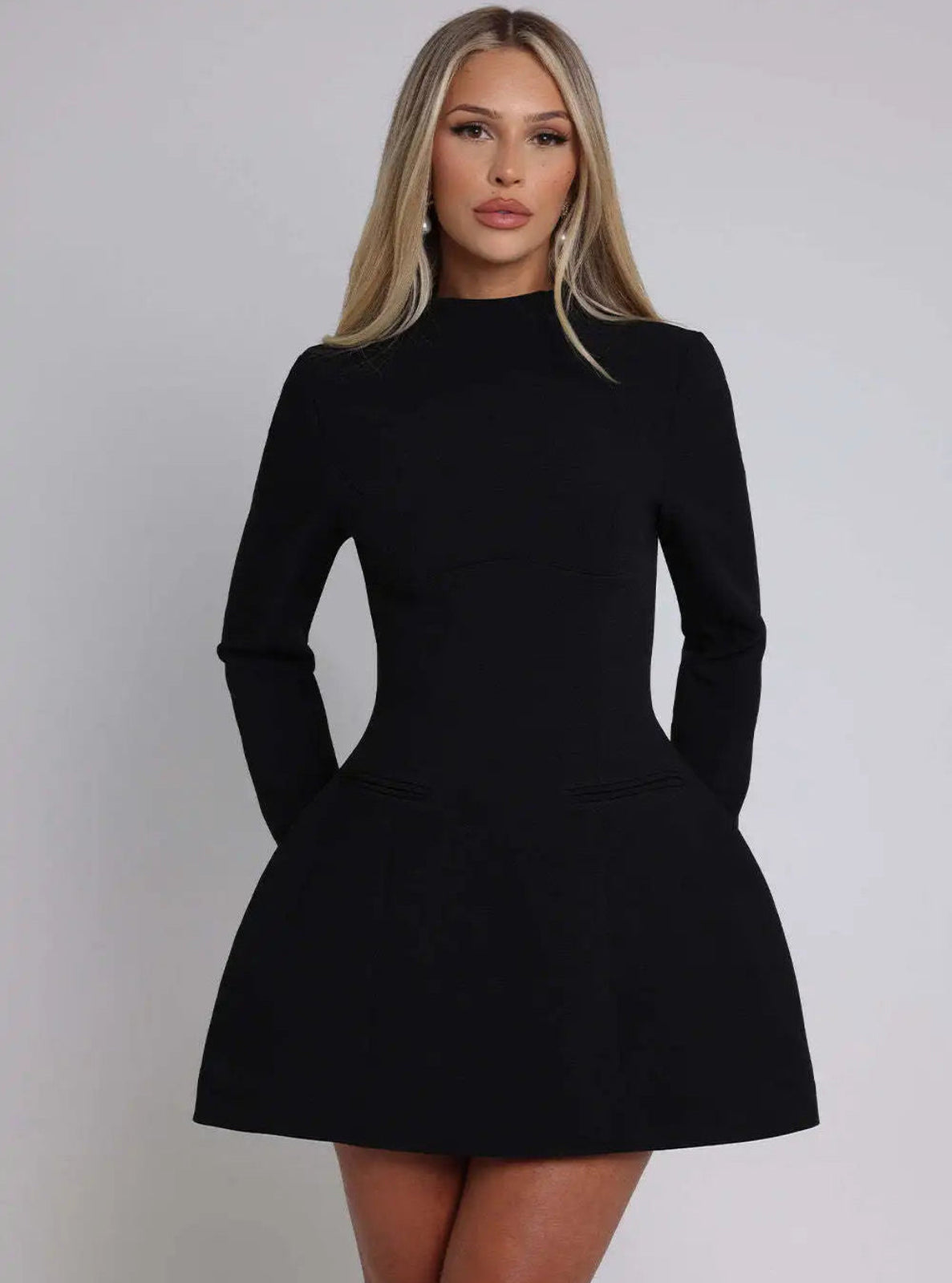Woman wearing a black dress against a plain background