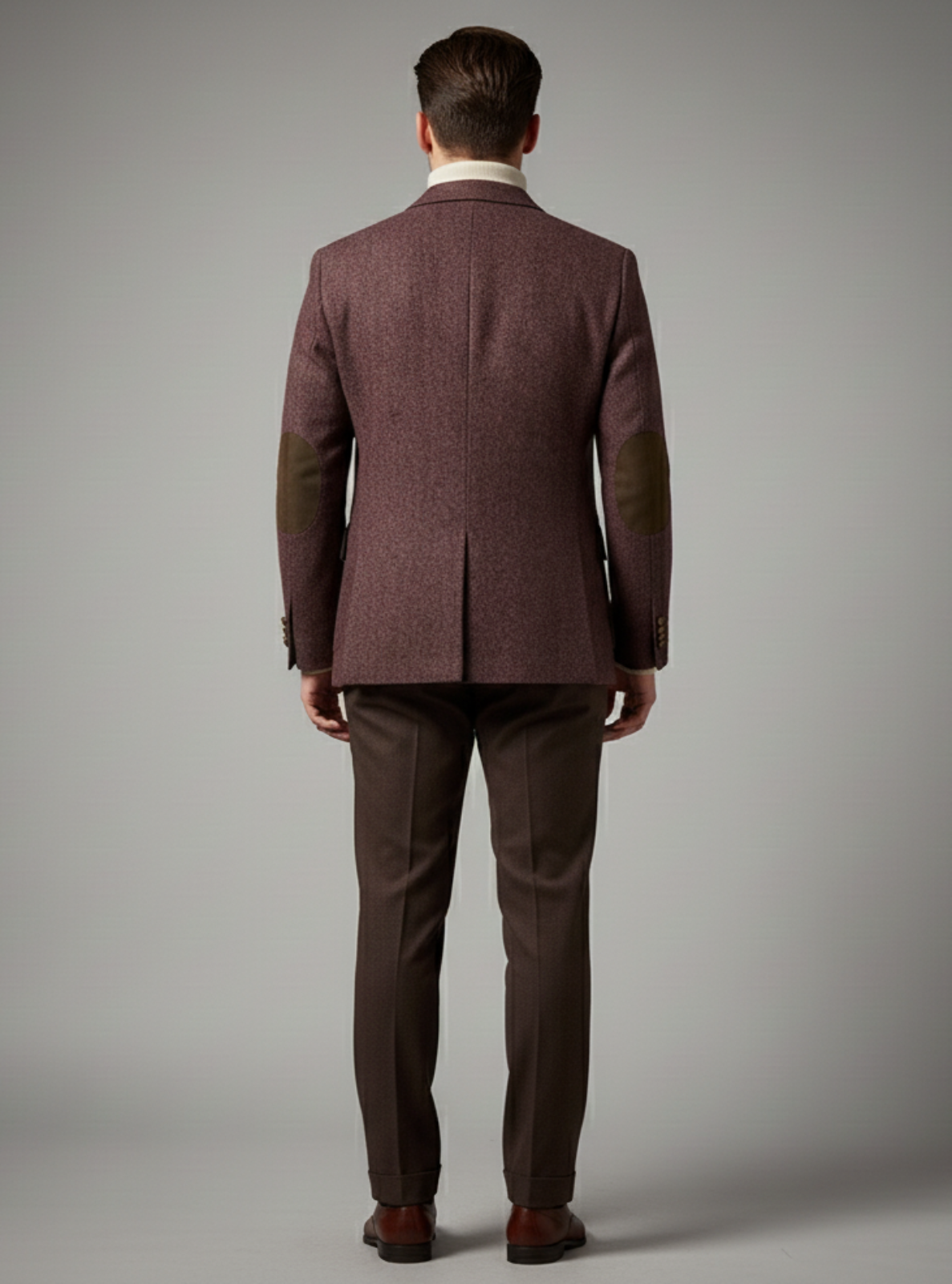 Man wearing a brown suit against a gray background