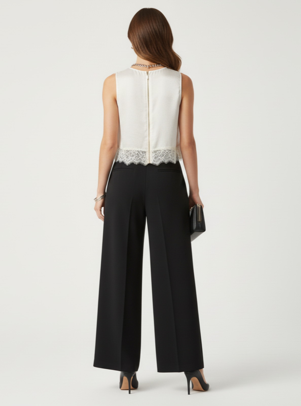 Woman wearing a white sleeveless top with lace detail and black pants on a white background