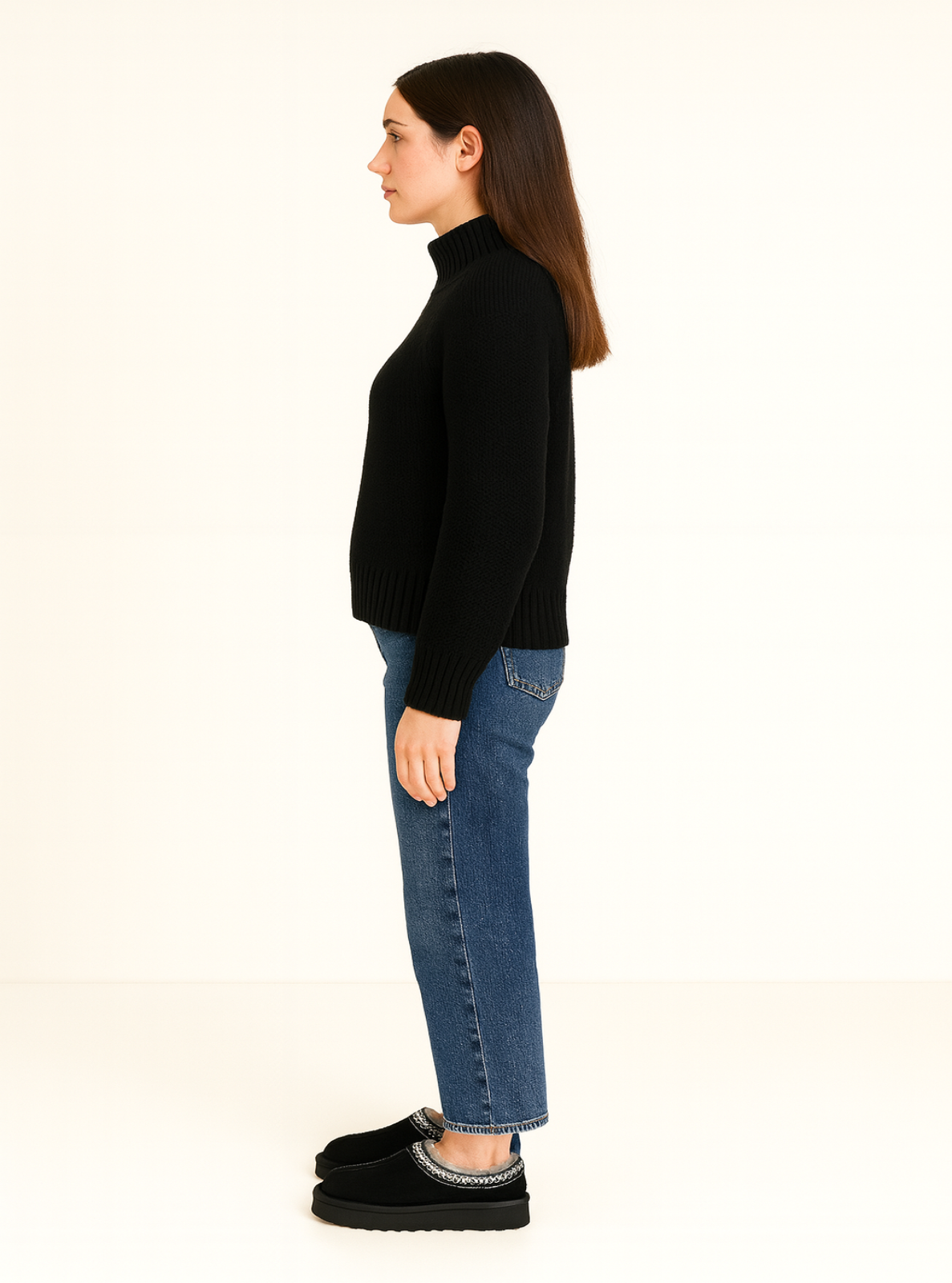 Person wearing a black turtleneck and blue jeans on a white background