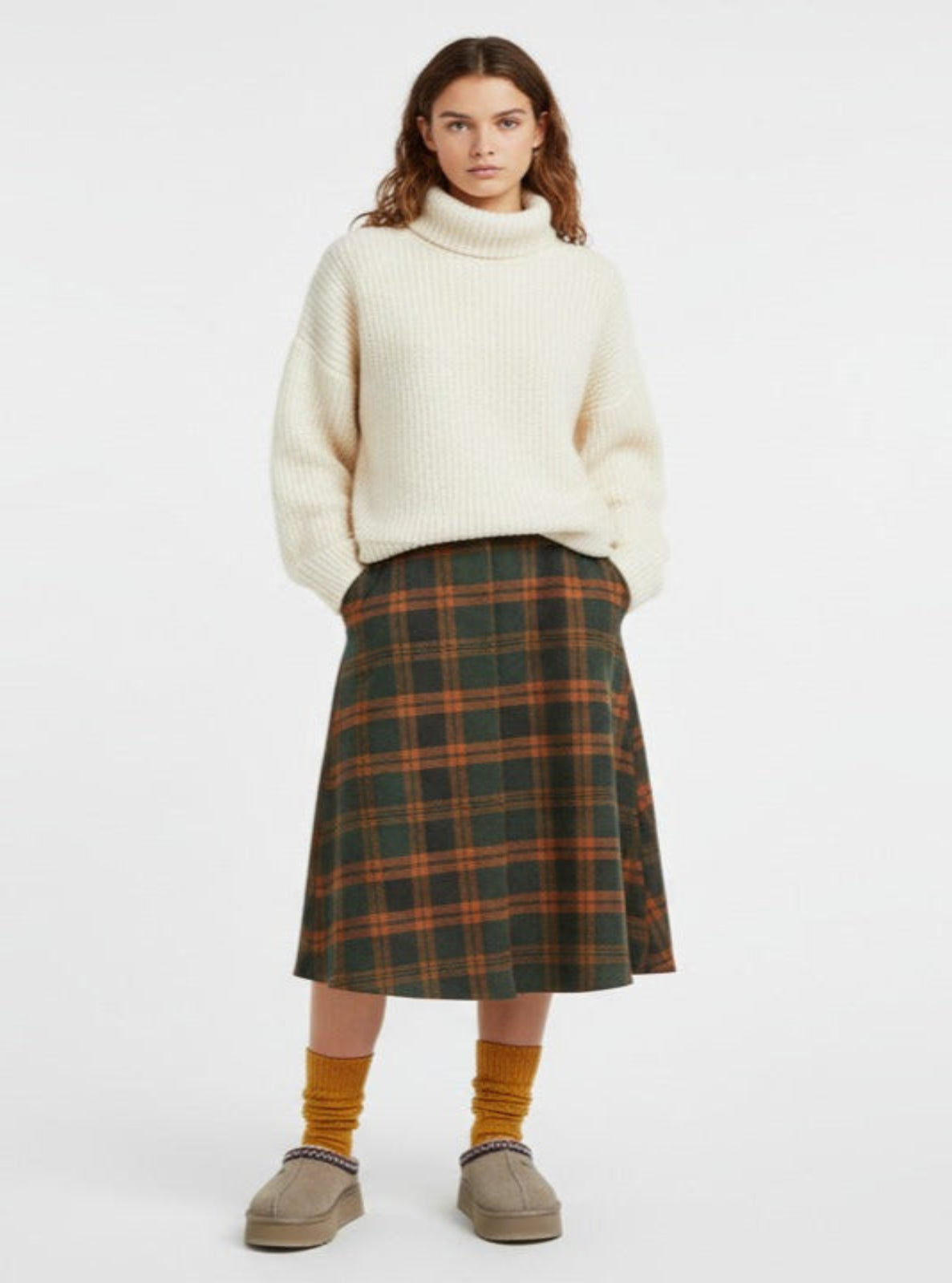 Woman wearing a white sweater and plaid skirt on a white background