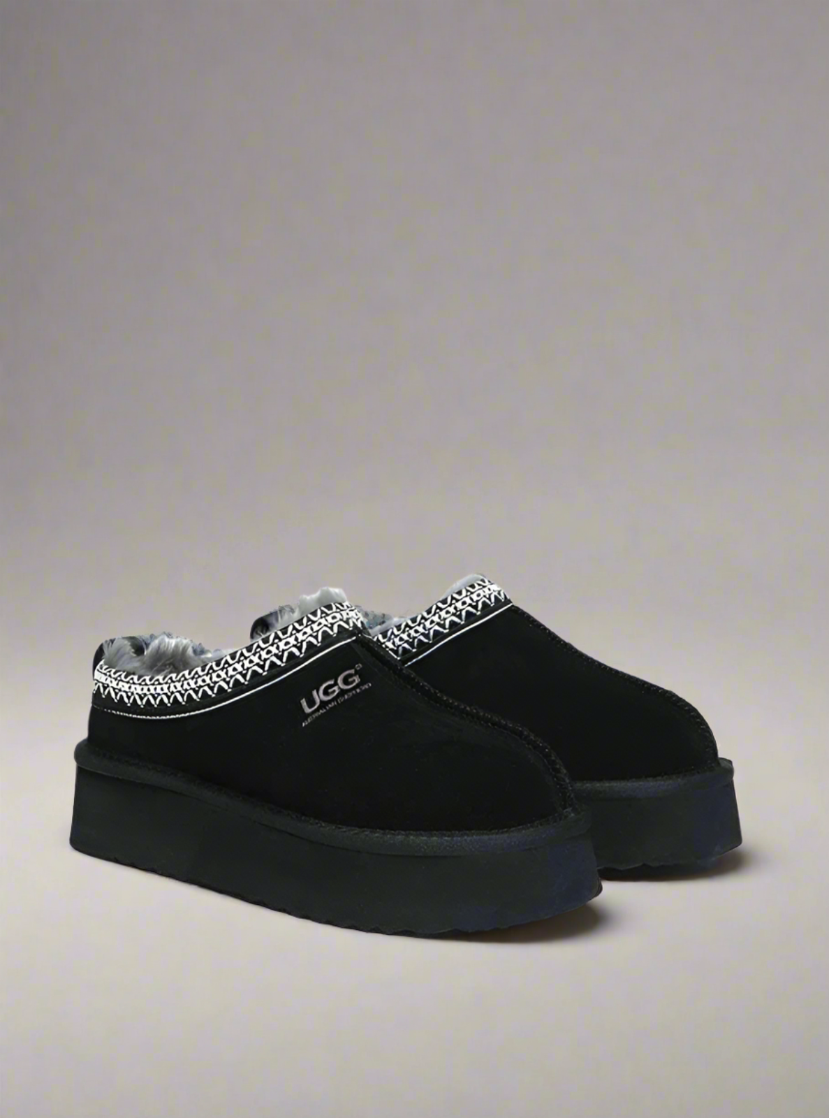 Black UGG slippers with patterned trim on a white background