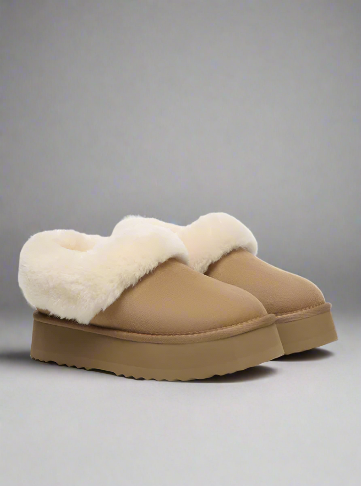 Pair of tan slippers with white fur lining on a white background