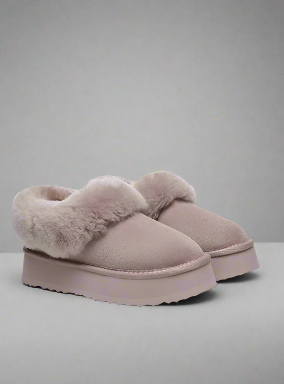 Pair of pink slippers with fluffy trim on a light gray background