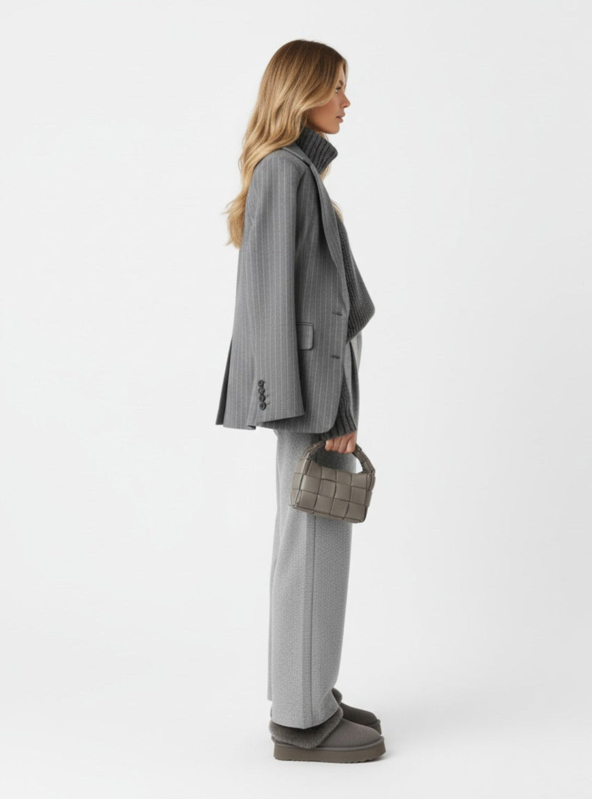 Woman wearing a gray suit with a matching handbag on a white background