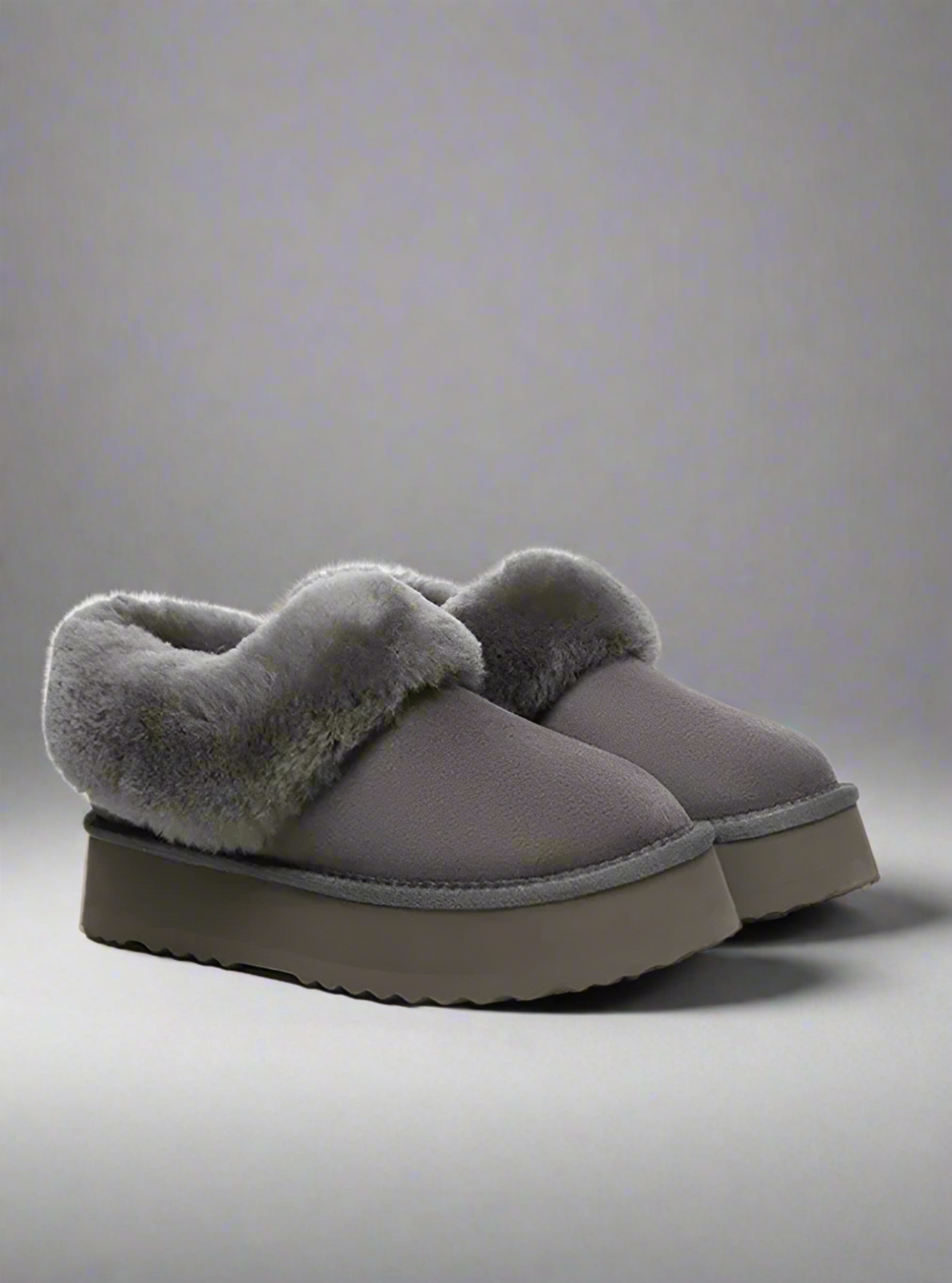 Pair of gray slippers with fuzzy texture on a light gray background