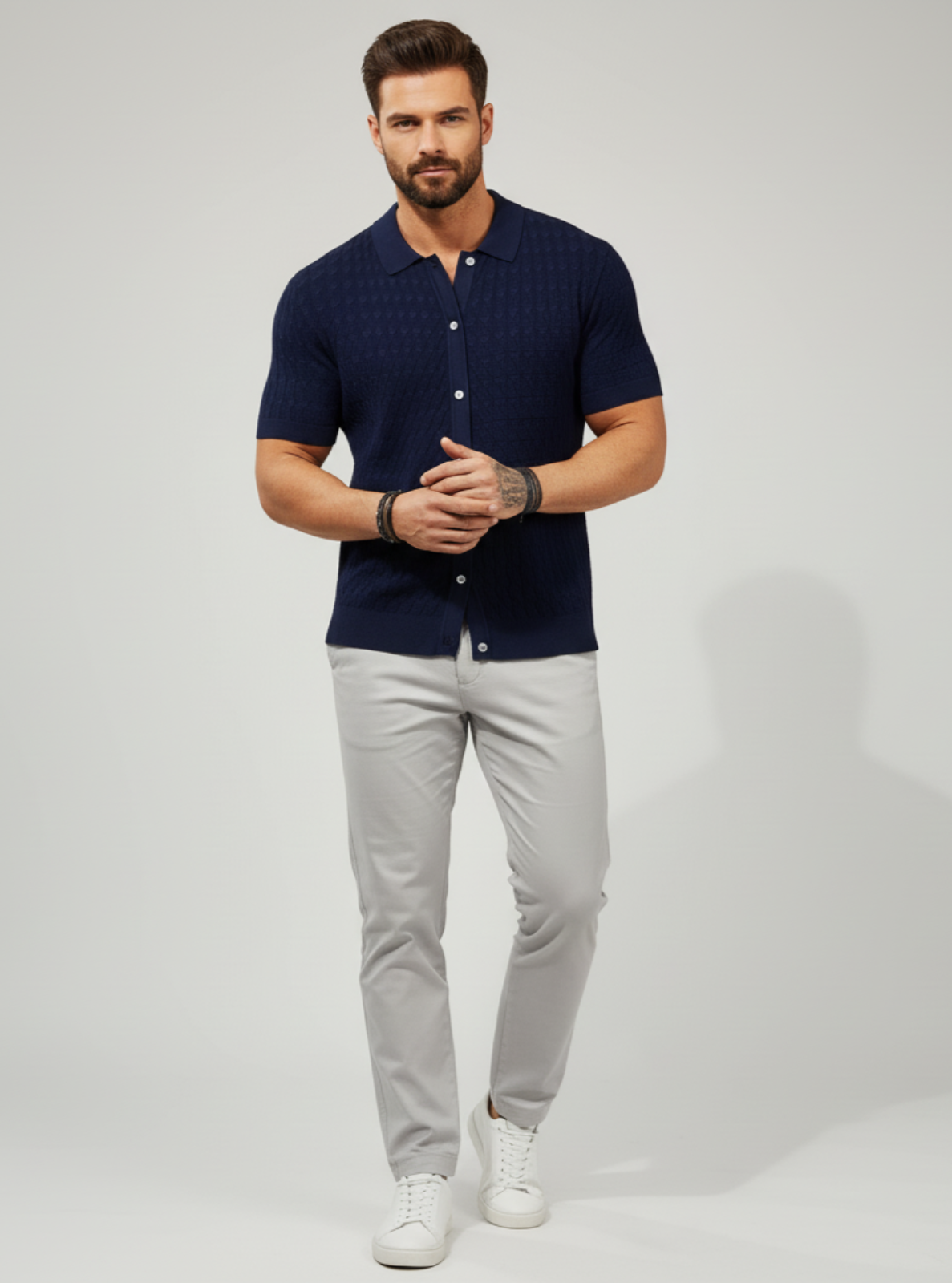 Man wearing a navy blue shirt and gray pants on a light gray background