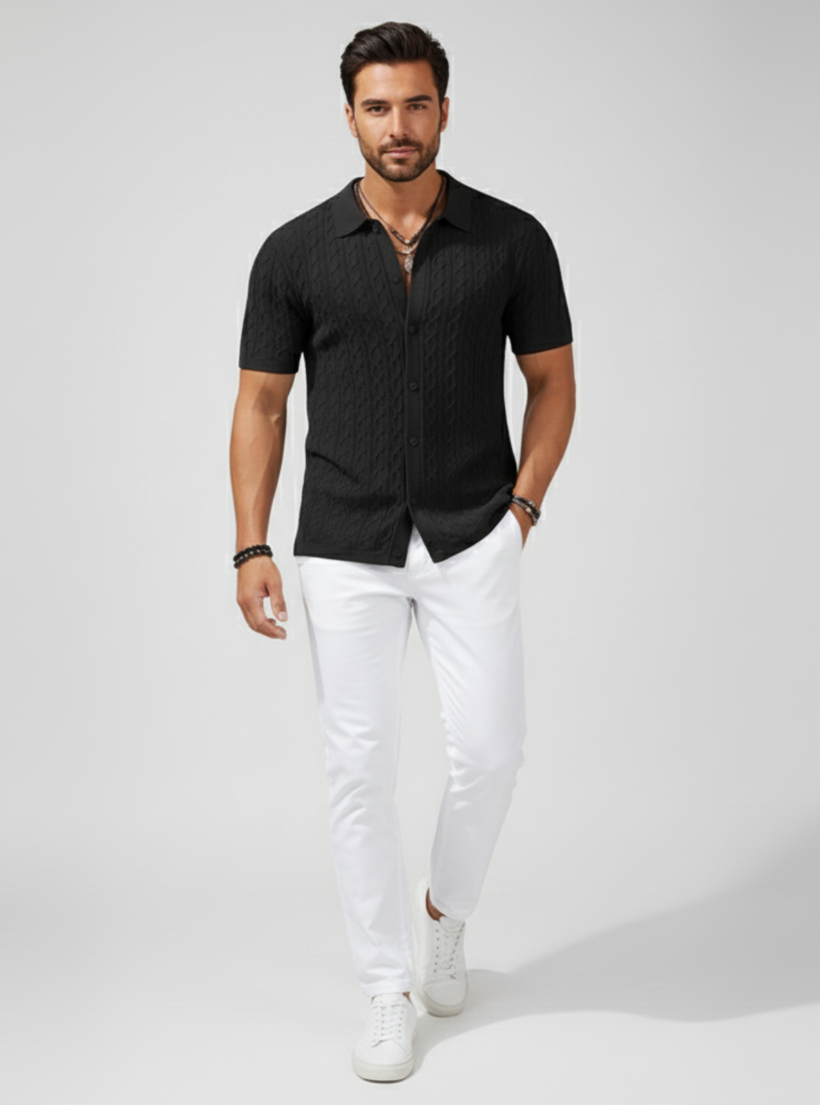 Man wearing a black short-sleeve shirt and white pants on a gray background