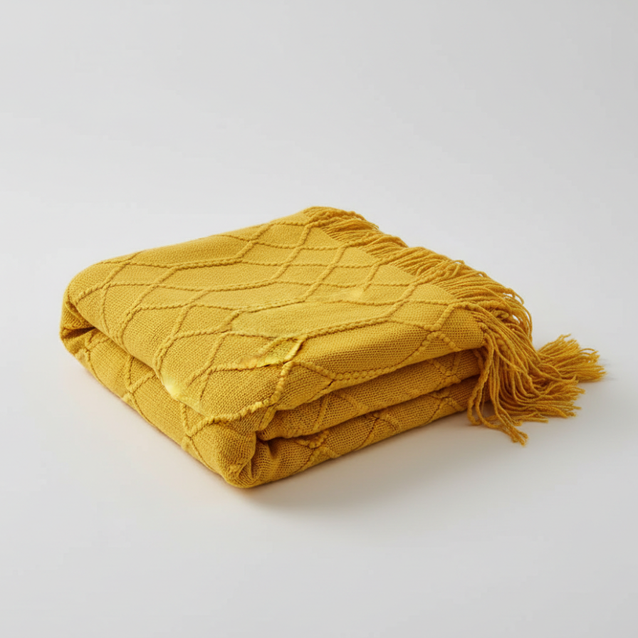 Yellow textured blanket with fringes on a light gray background