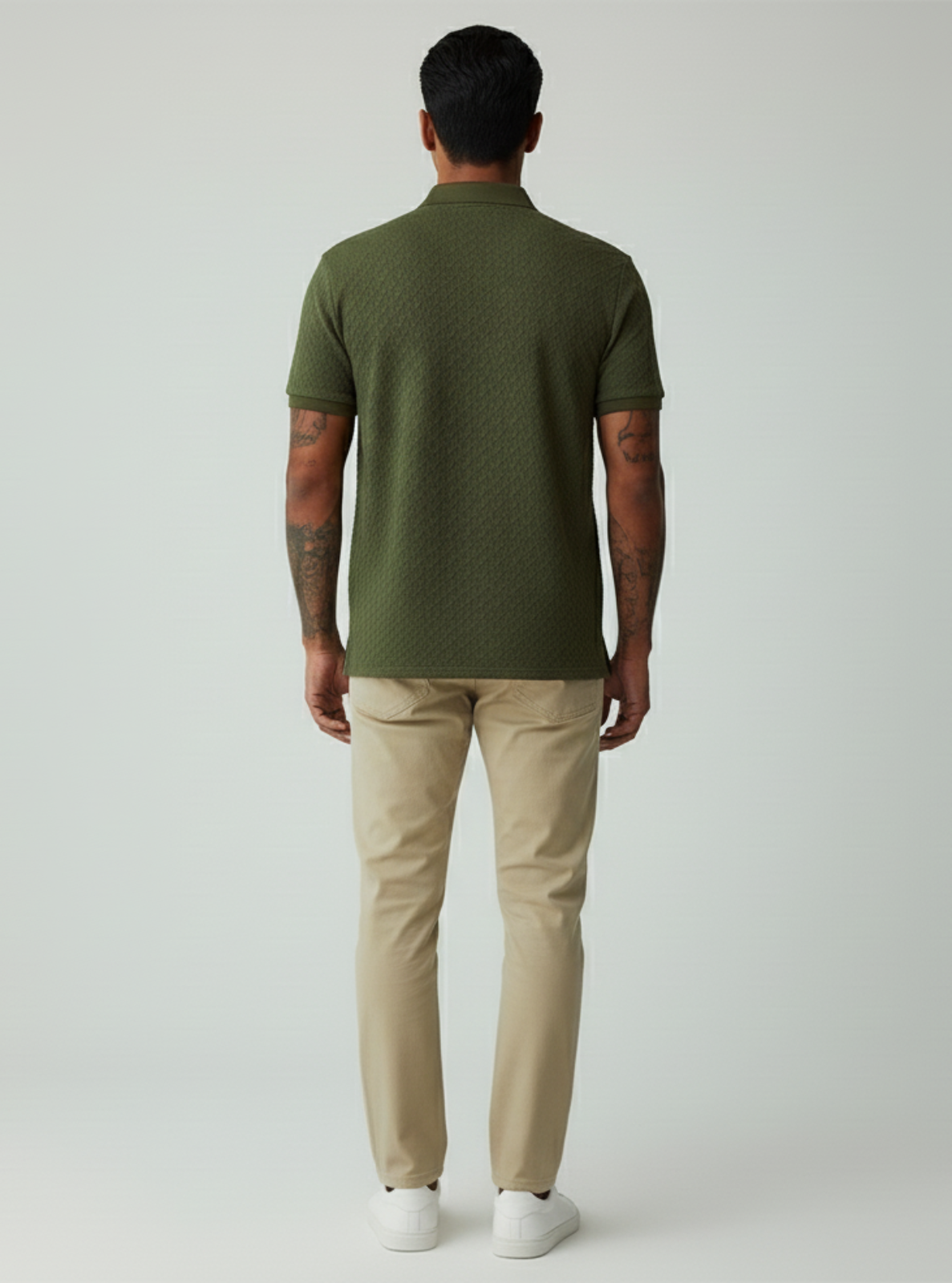 Man wearing a green polo shirt and beige pants on a white background