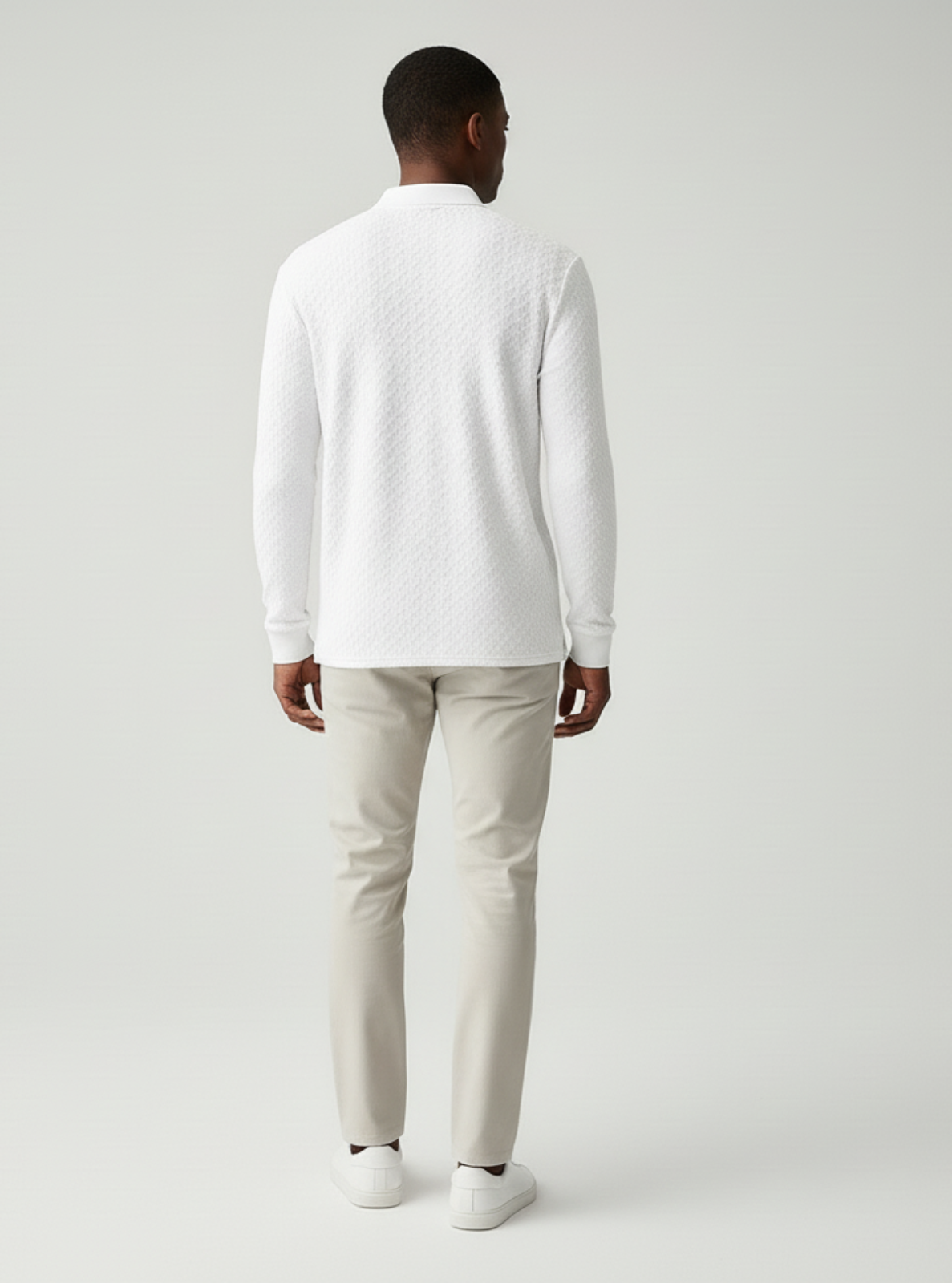 Man wearing a white long-sleeve shirt and light gray pants on a plain background