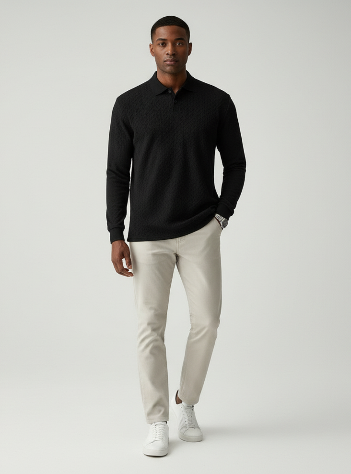Man wearing a black long-sleeve shirt and beige pants on a white background