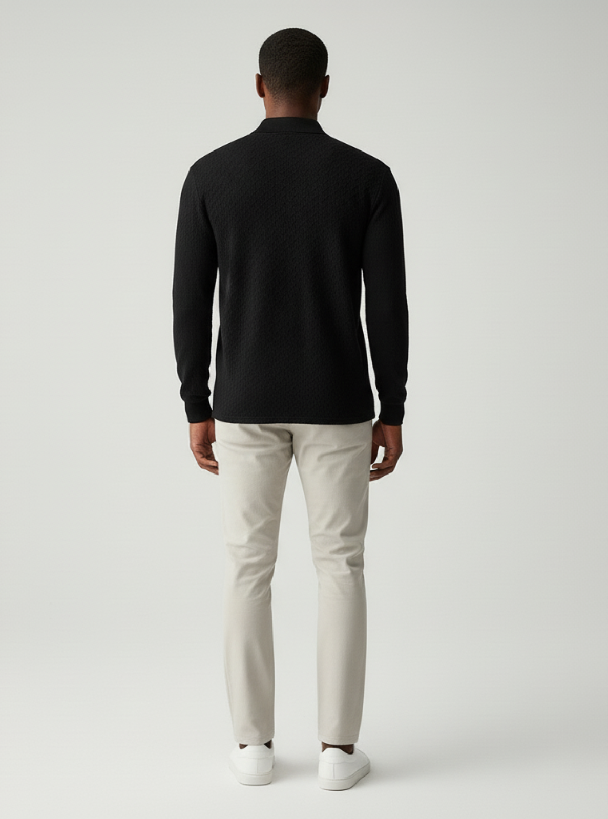 Man wearing a black long-sleeve shirt and light-colored pants on a white background