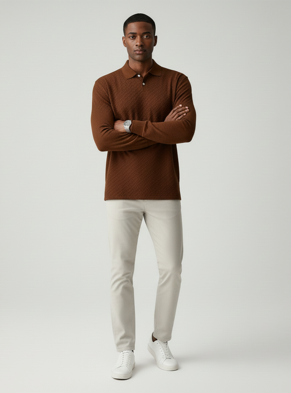 Man wearing a brown polo shirt and white pants on a light gray background
