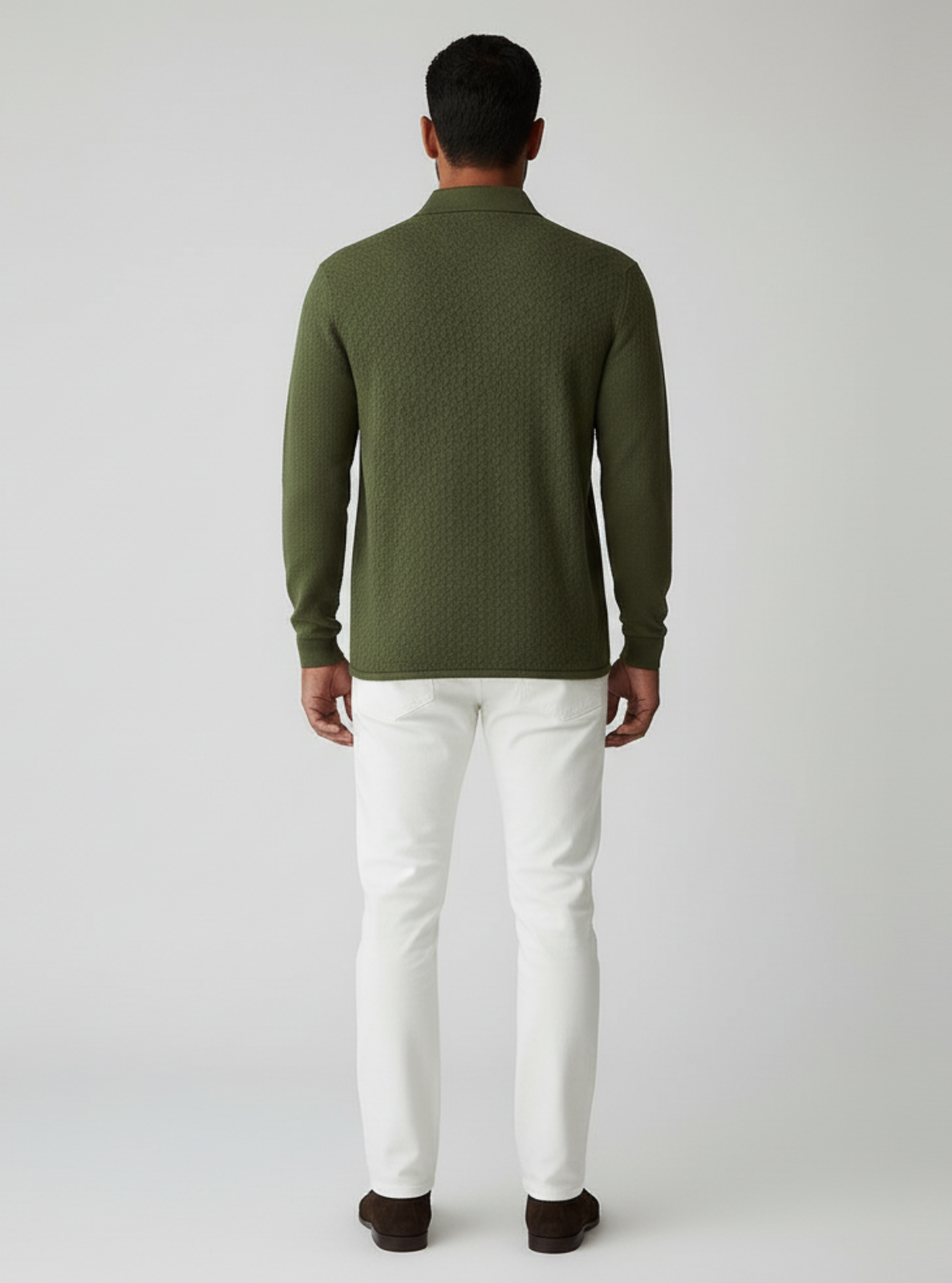 Man wearing a green sweater and white pants on a light gray background