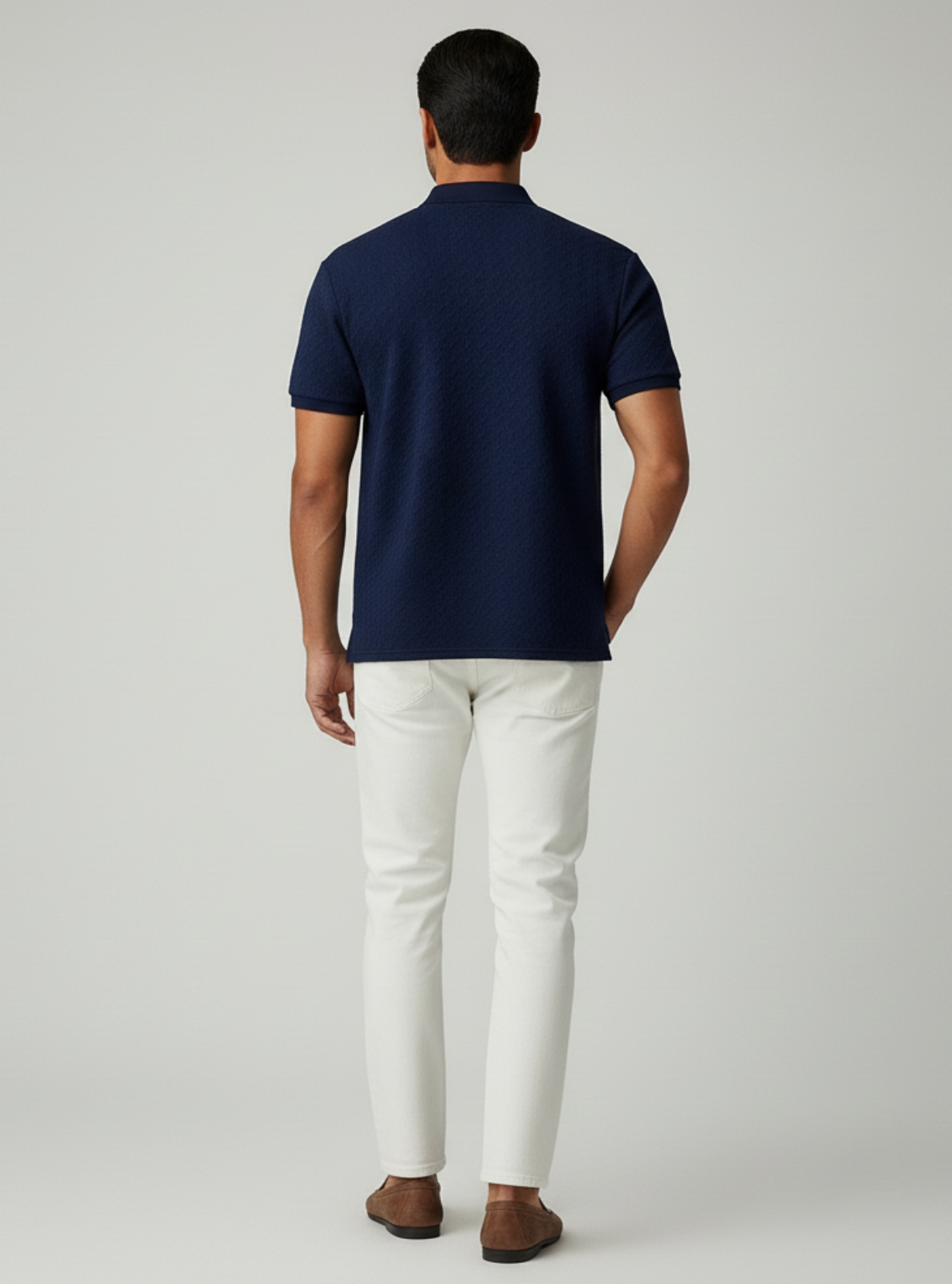 Man wearing a navy polo shirt and white pants on a light gray background