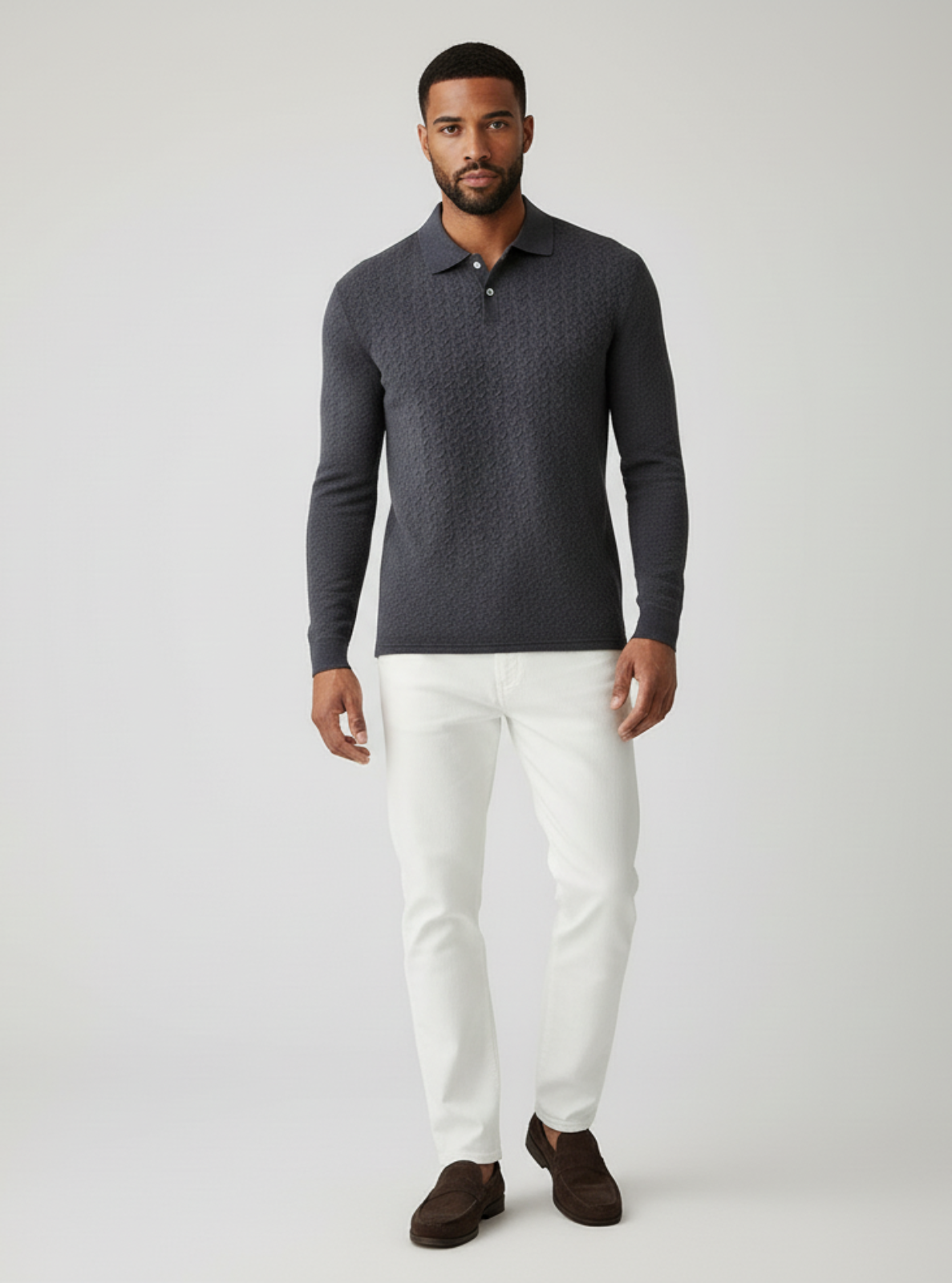 Man wearing a dark gray long-sleeve polo shirt and white pants on a light gray background