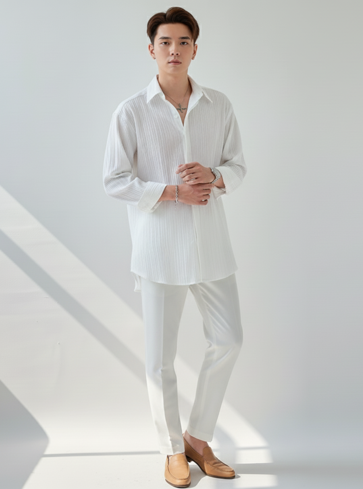 Man wearing a white shirt and pants in a minimalistic setting