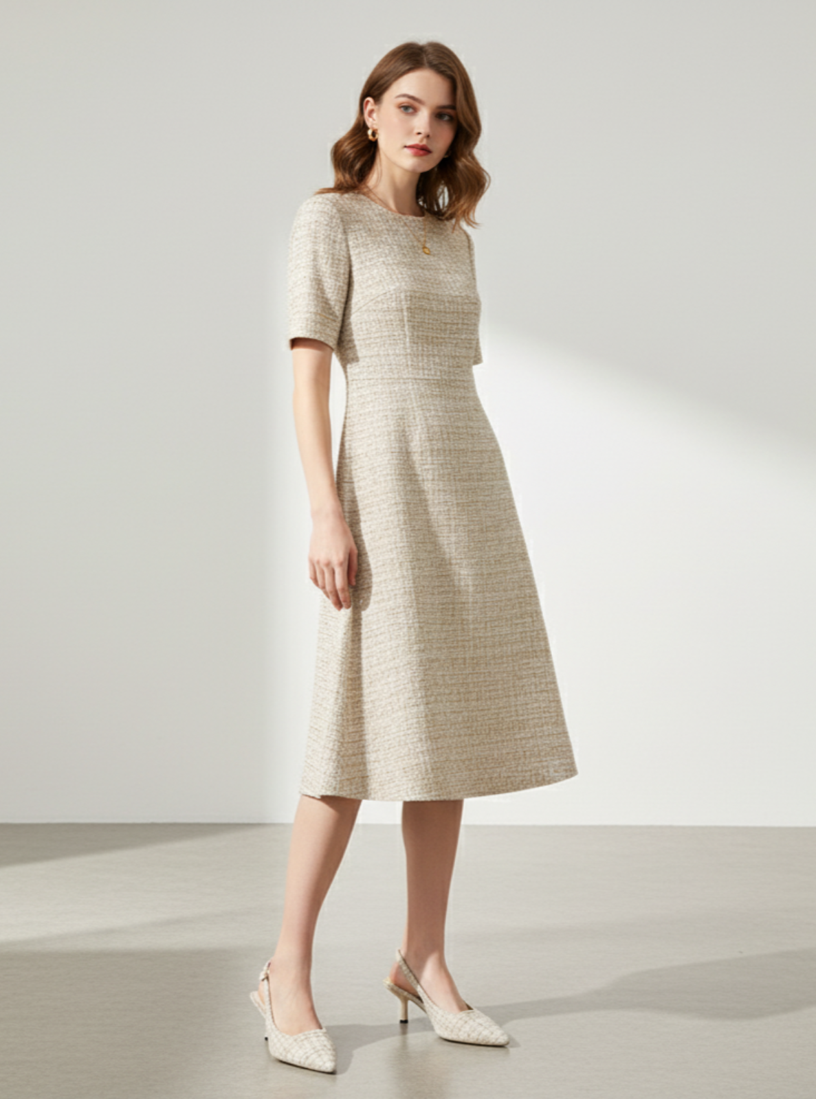 Woman wearing a beige checkered dress on a plain background